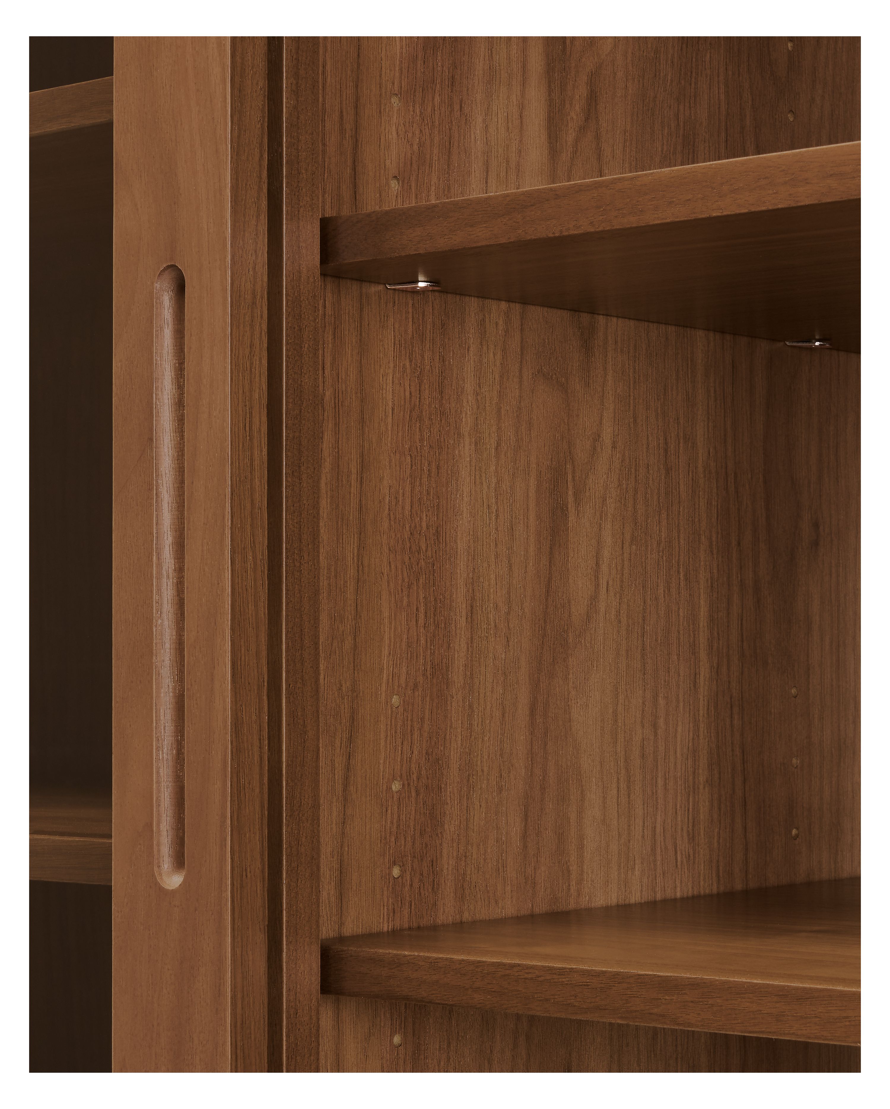 Emerson storage cabinet in walnut showing underside of shelves and shelf pins.