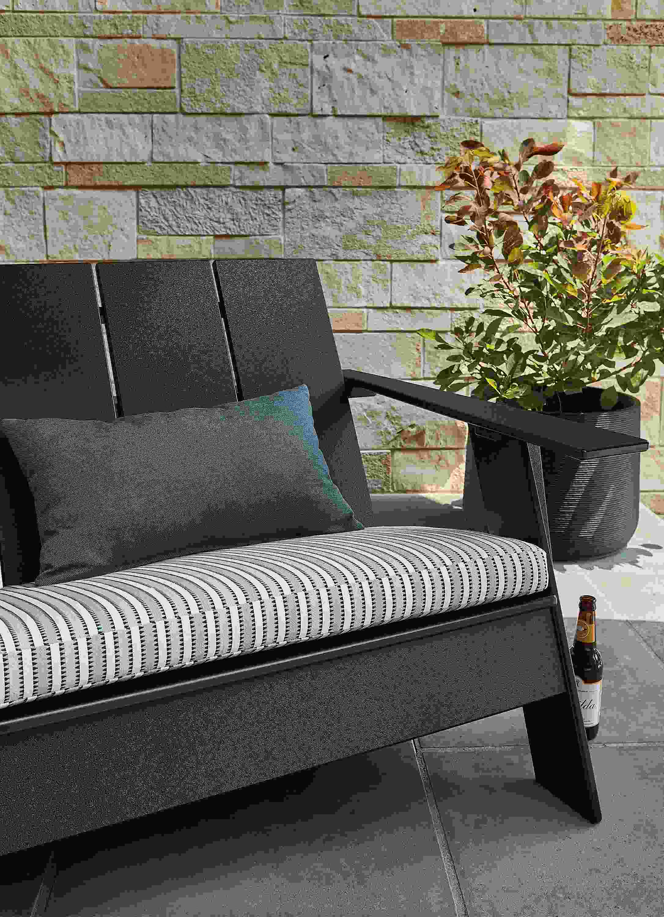 Outdoor space with Emmet sofa in black with cushion, and Ajax planter.