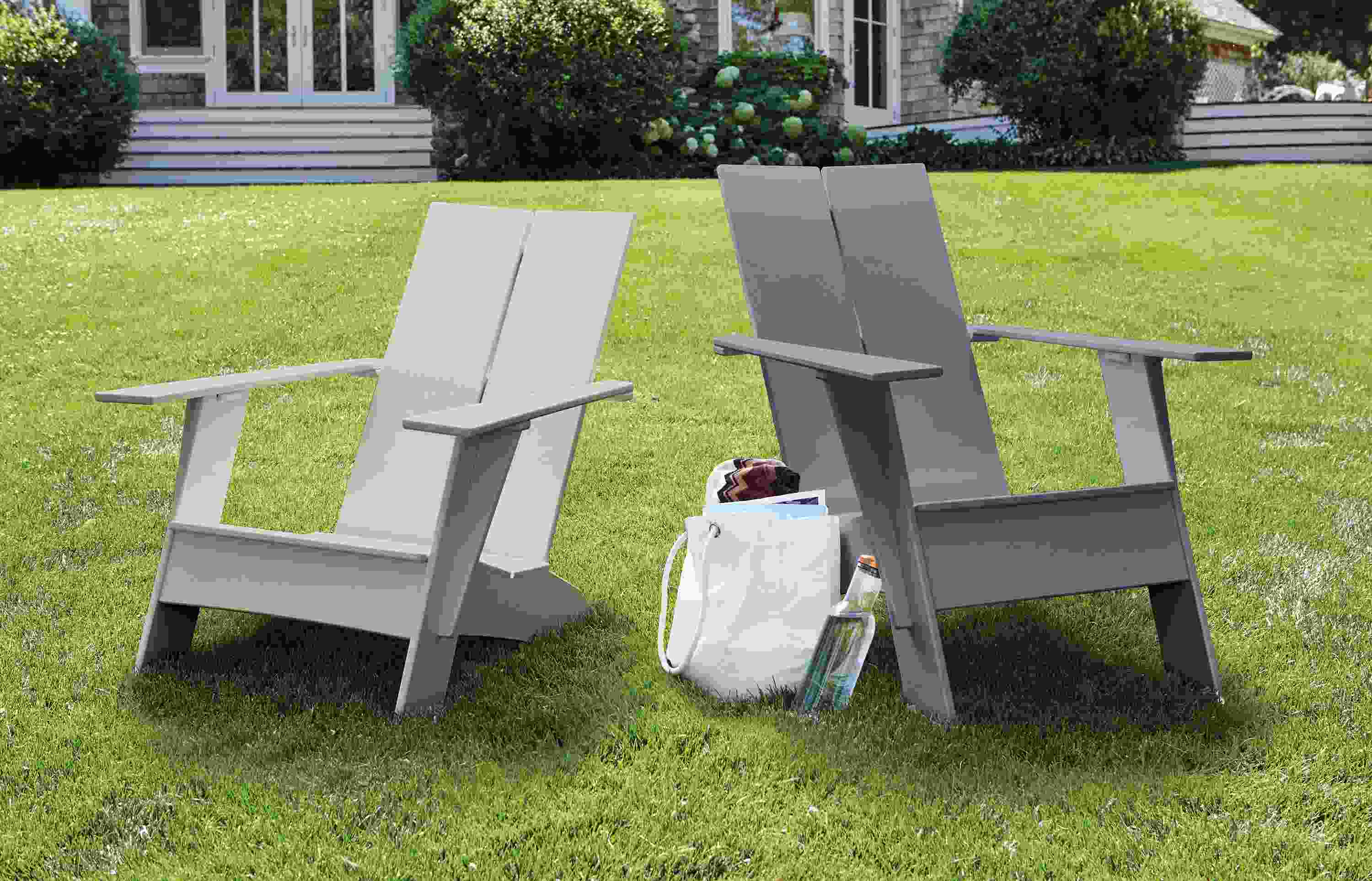 Emmet tall and short outdoor lounge chairs in fog and slate on a lawn.