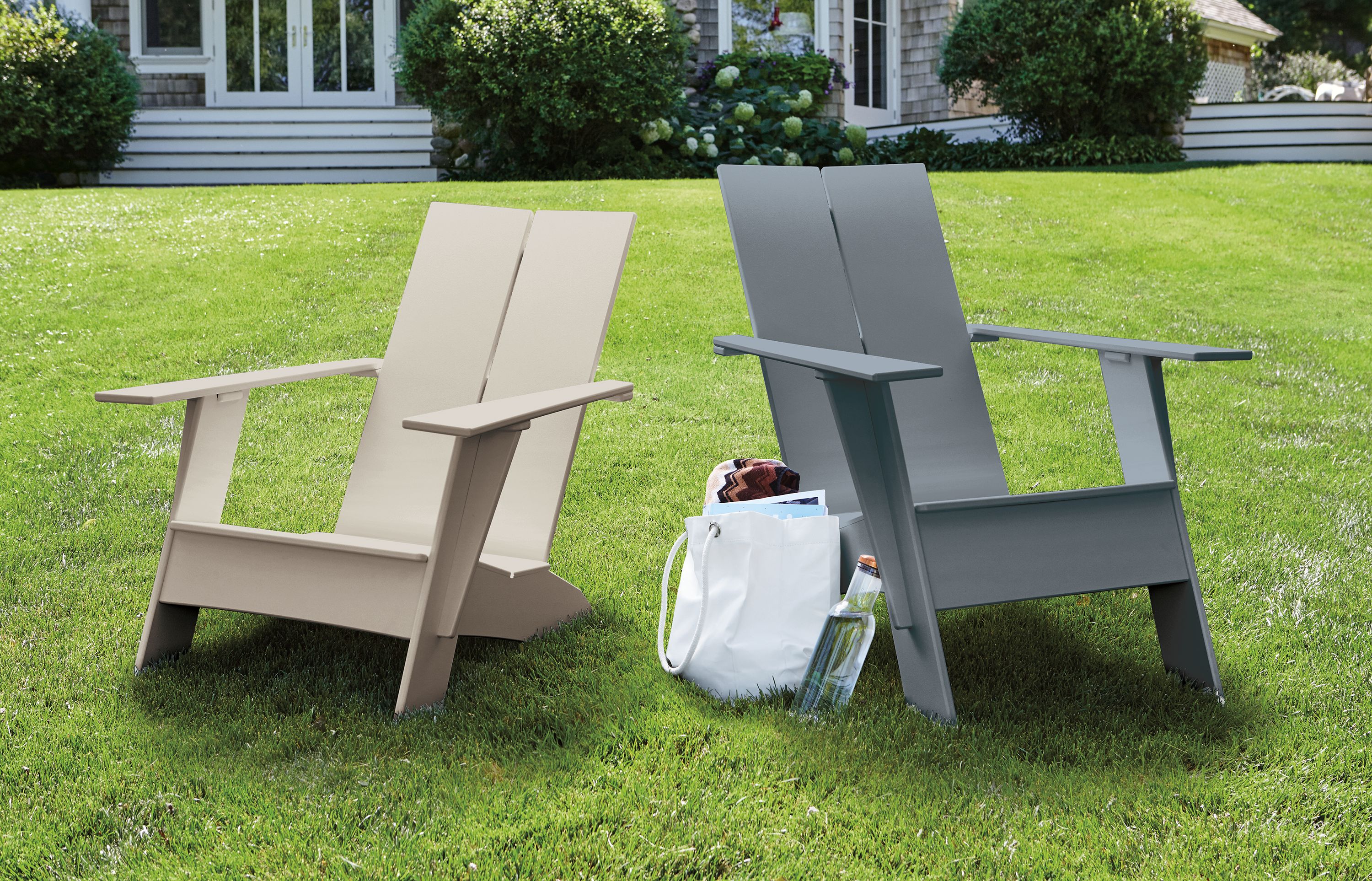 Emmet tall and short outdoor lounge chairs in fog and slate on a lawn.