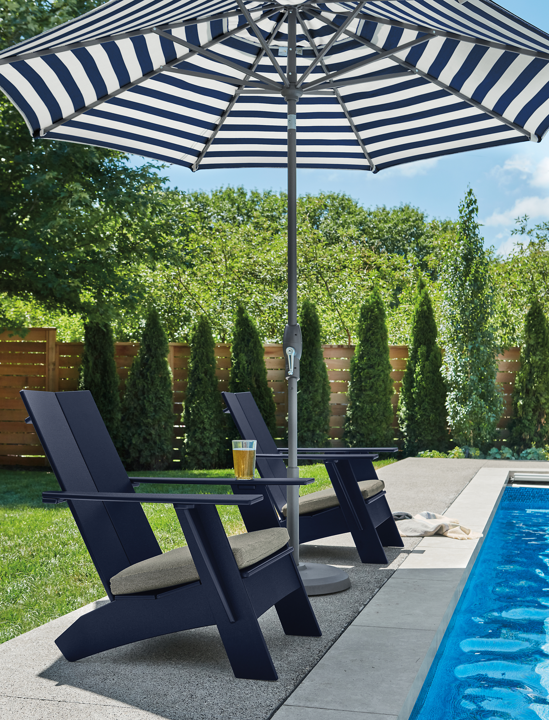 Two Emmet lounge chairs in Navy with Pelham grey fabric and Oahu 9-foot patio umbrella in Watts navy.