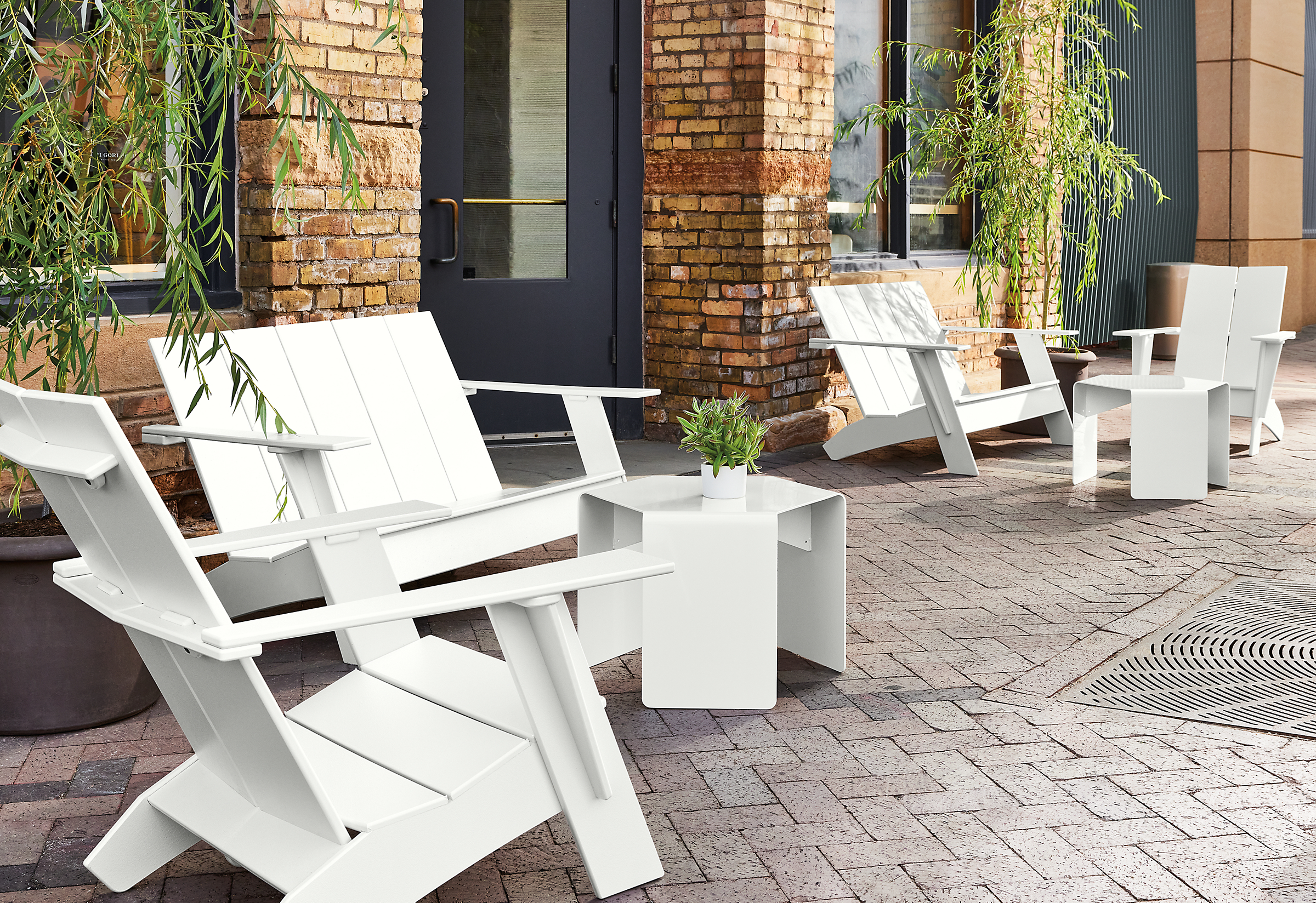 Outdoor space with several emmet sofas and chairs in white, with cell outdoor side tables and gilyard planters.