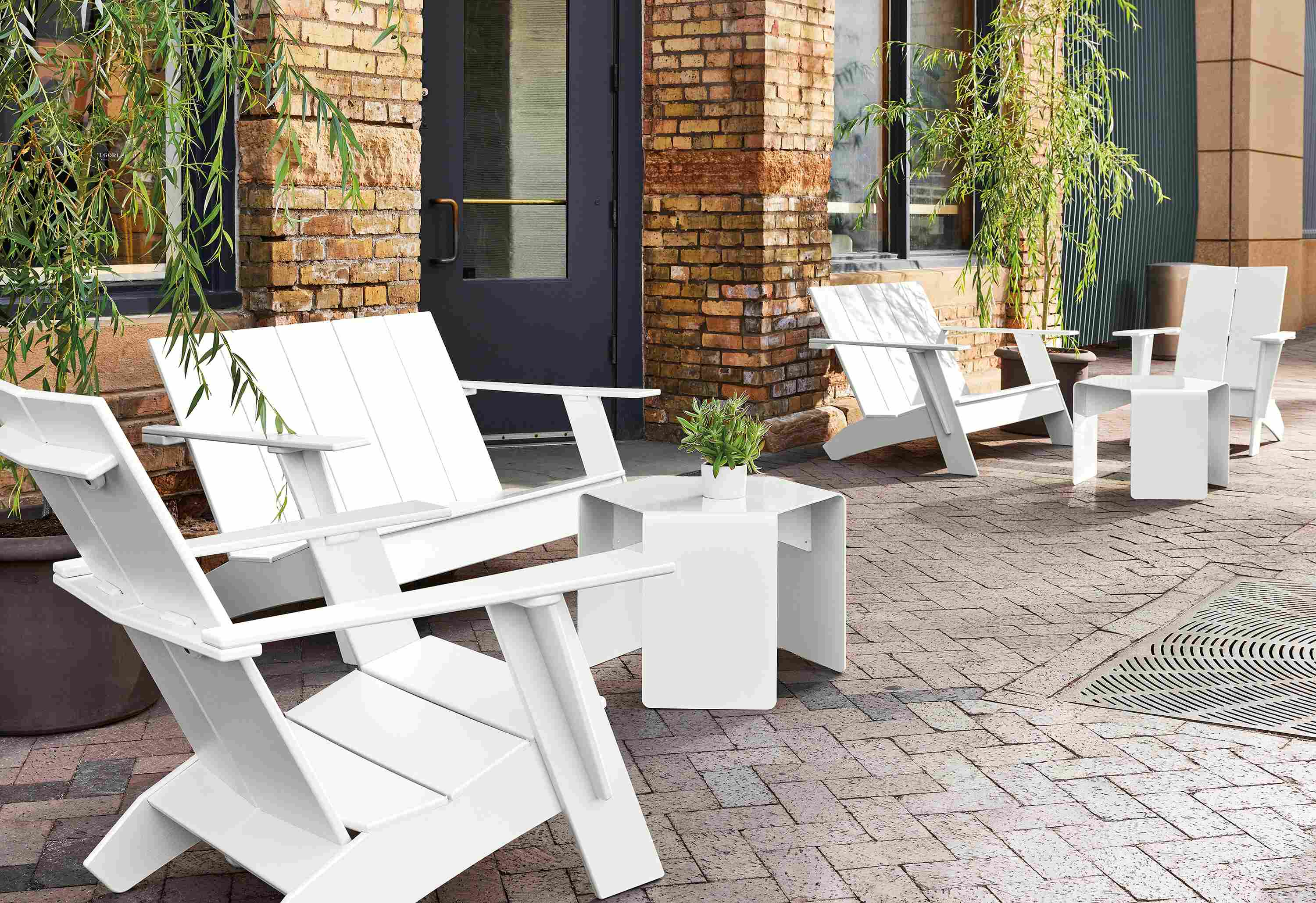 Outdoor space with several Emmet sofas and chairs in white, with cell outdoor side tables and Gilyard planters.