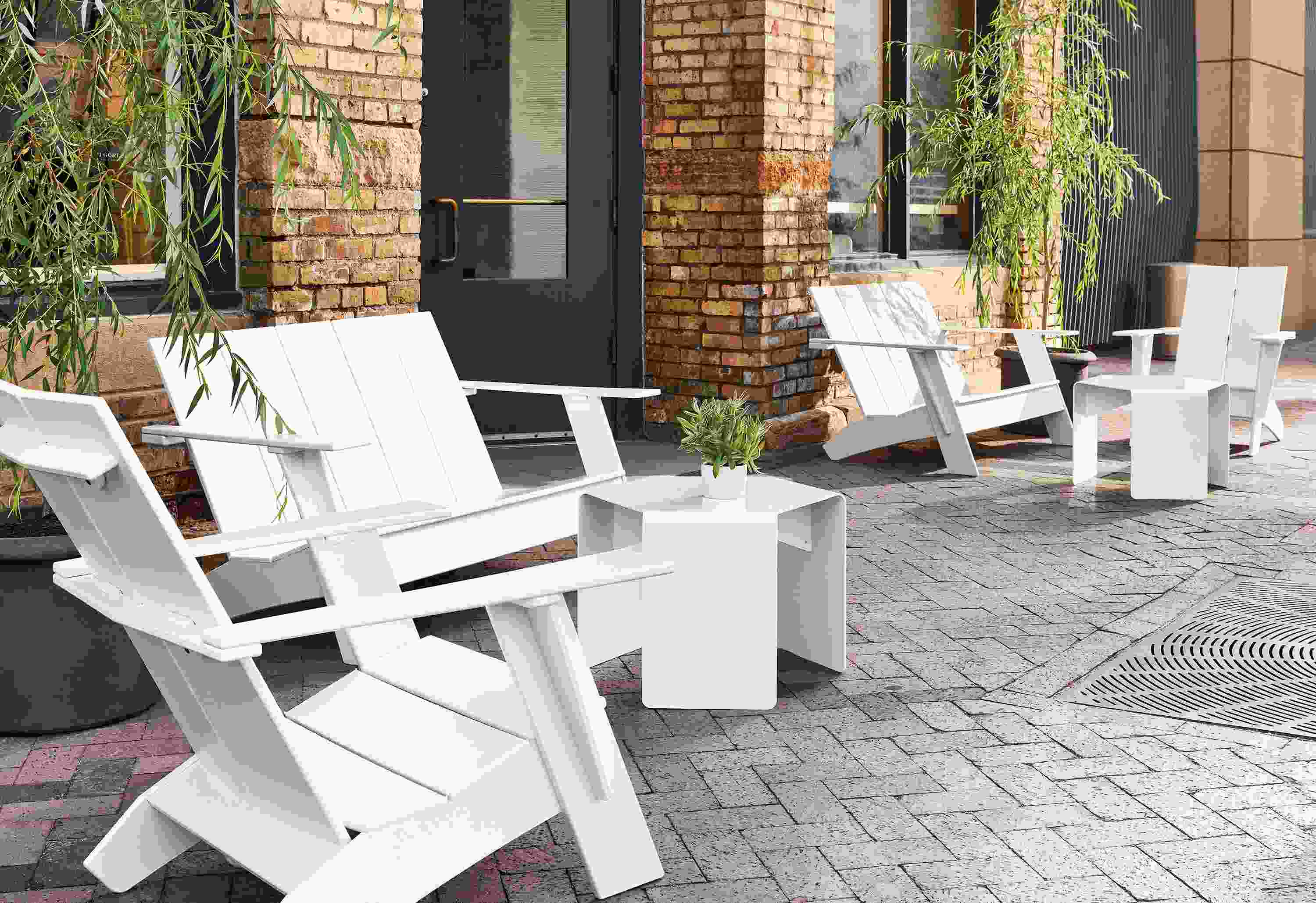 Outdoor space with several Emmet sofas and chairs in white, with cell outdoor side tables and Gilyard planters.