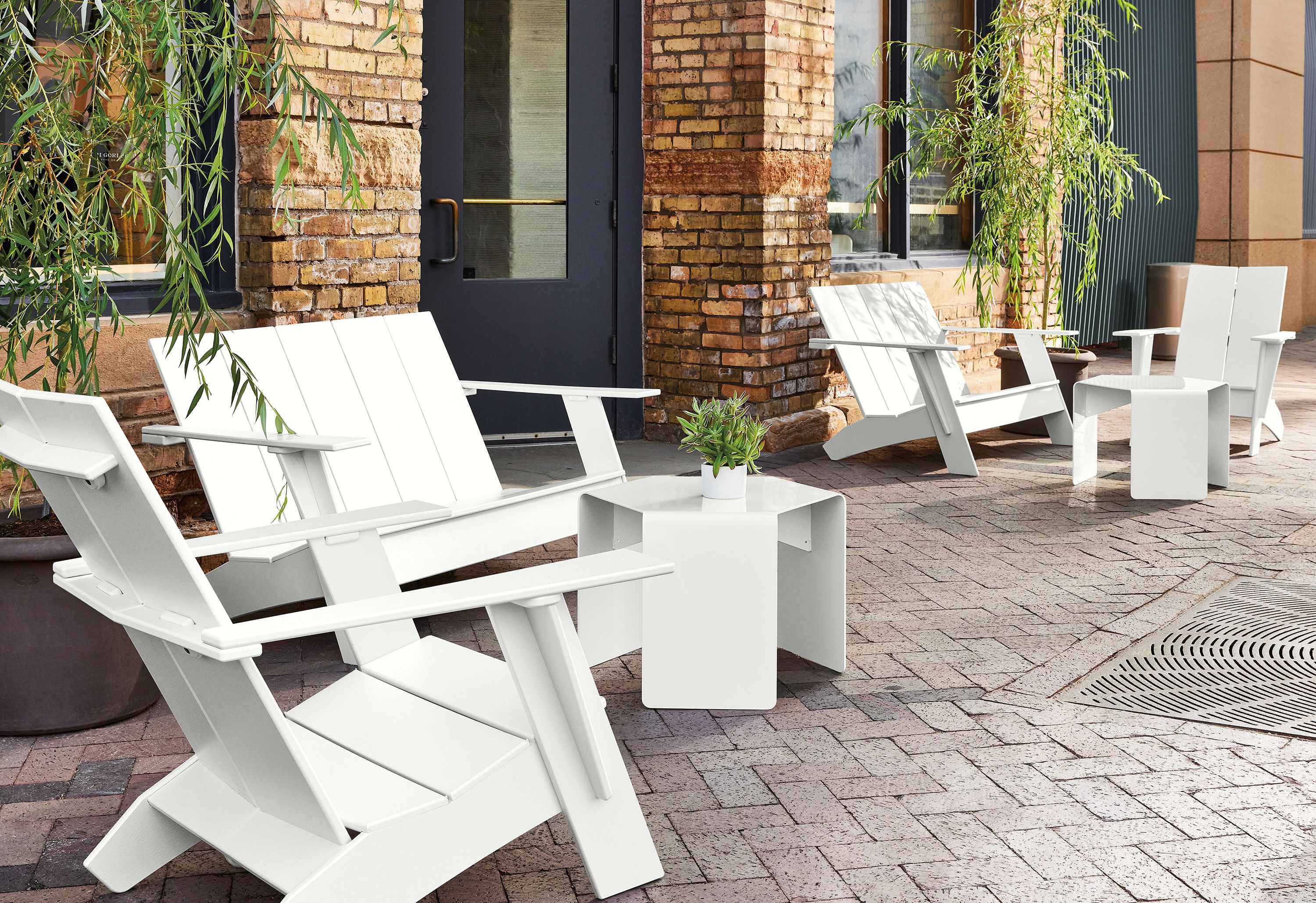 Outdoor space with several emmet sofas and chairs in white, with cell outdoor side tables and gilyard planters.