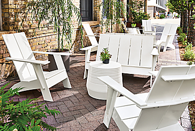 outdoor brick walkway with several white emmet sofas, chairs and a cusp stool.