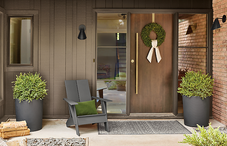 Emmet outdoor lounge chair, two furrow round planters in grey and Fara rug in carbon on front porch.