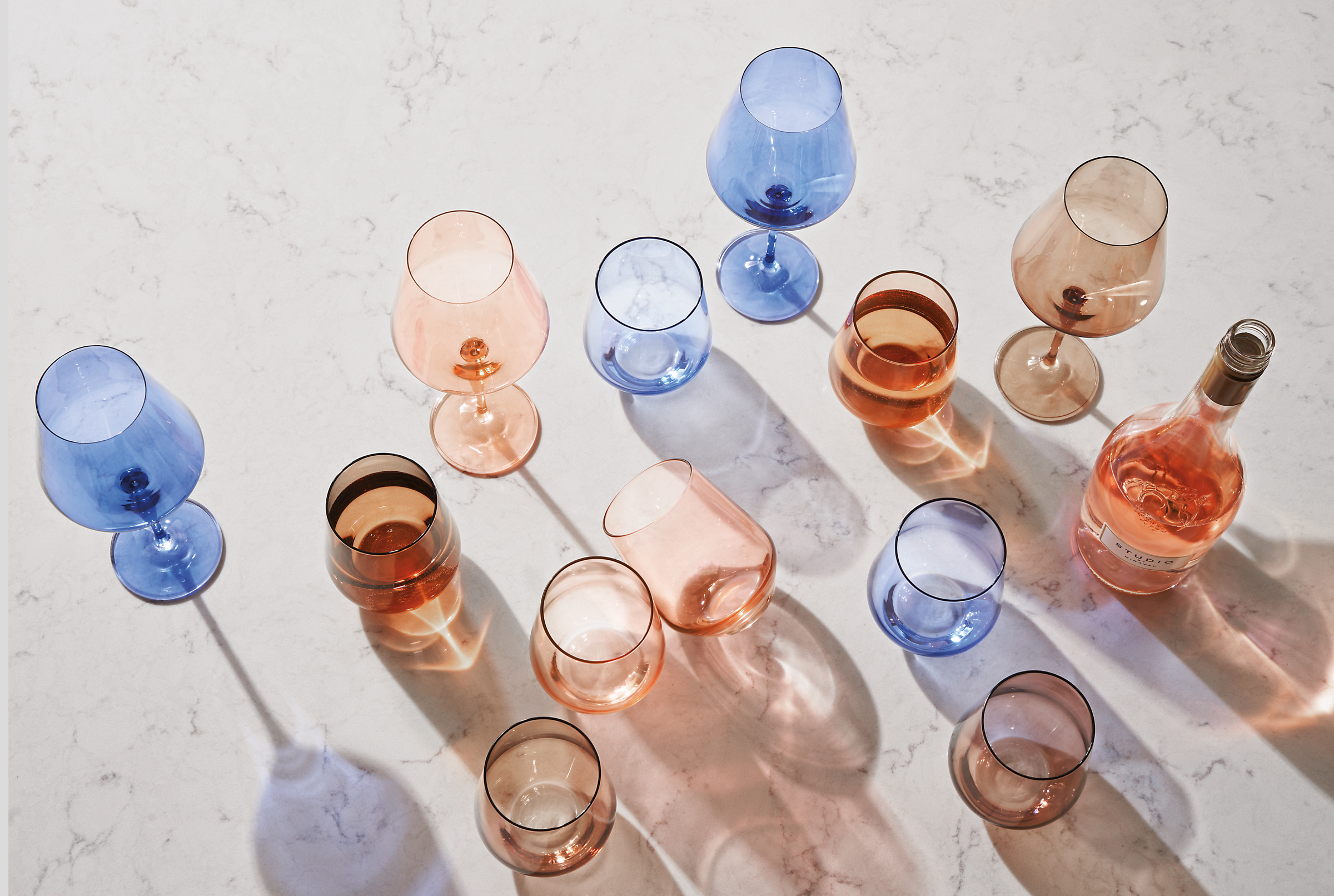 detail of estelle glassware in blue, blush and amber on marbled white quartz tabletop.