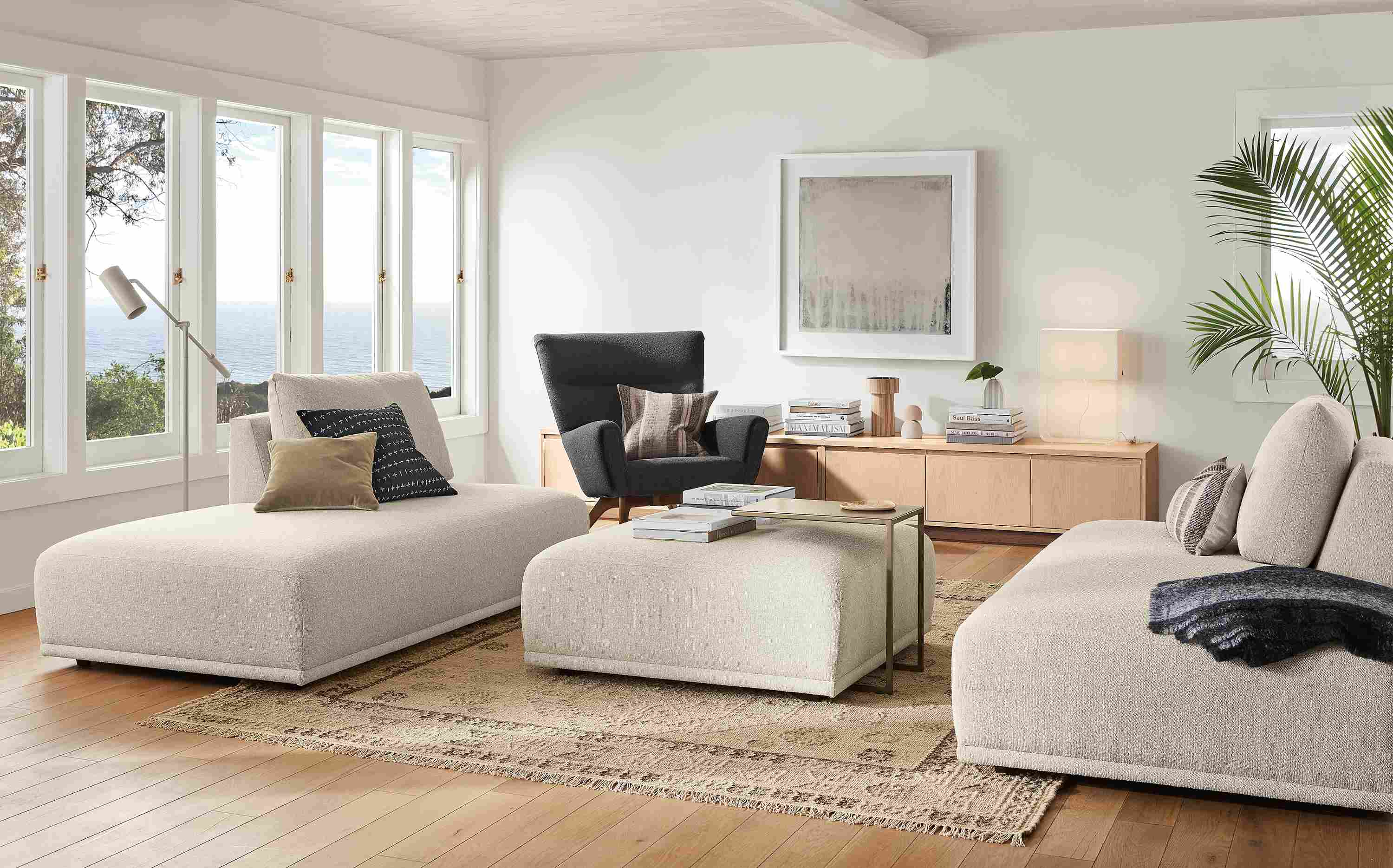 Living room with Fia sofas and ottoman in Conley Natural, Boden chair in Declan Graphite and Keaton media cabinet salt on red oak.