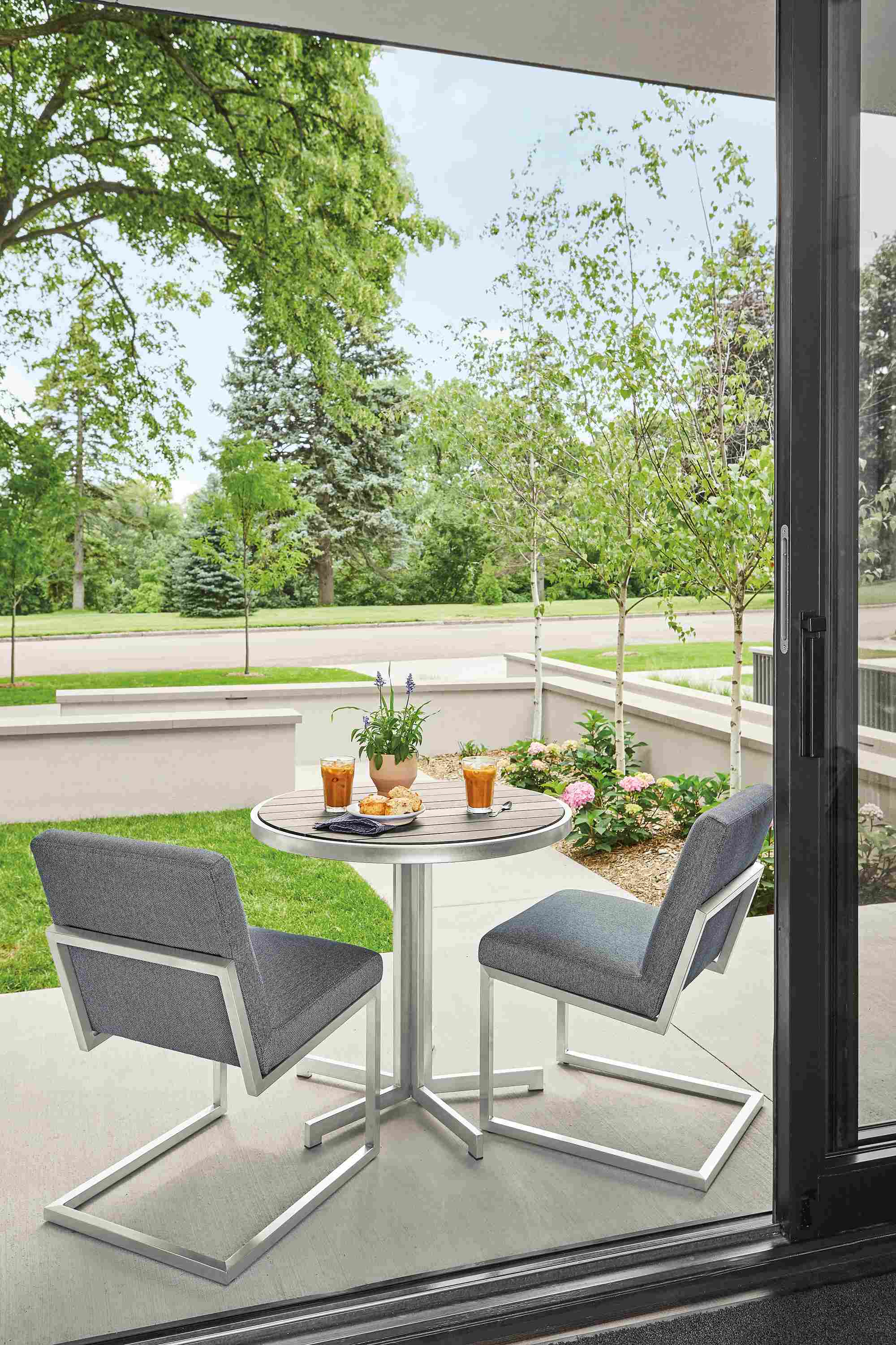 Outdoor patio with Finn side chairs in mist fabric and montego round table in aged ash.