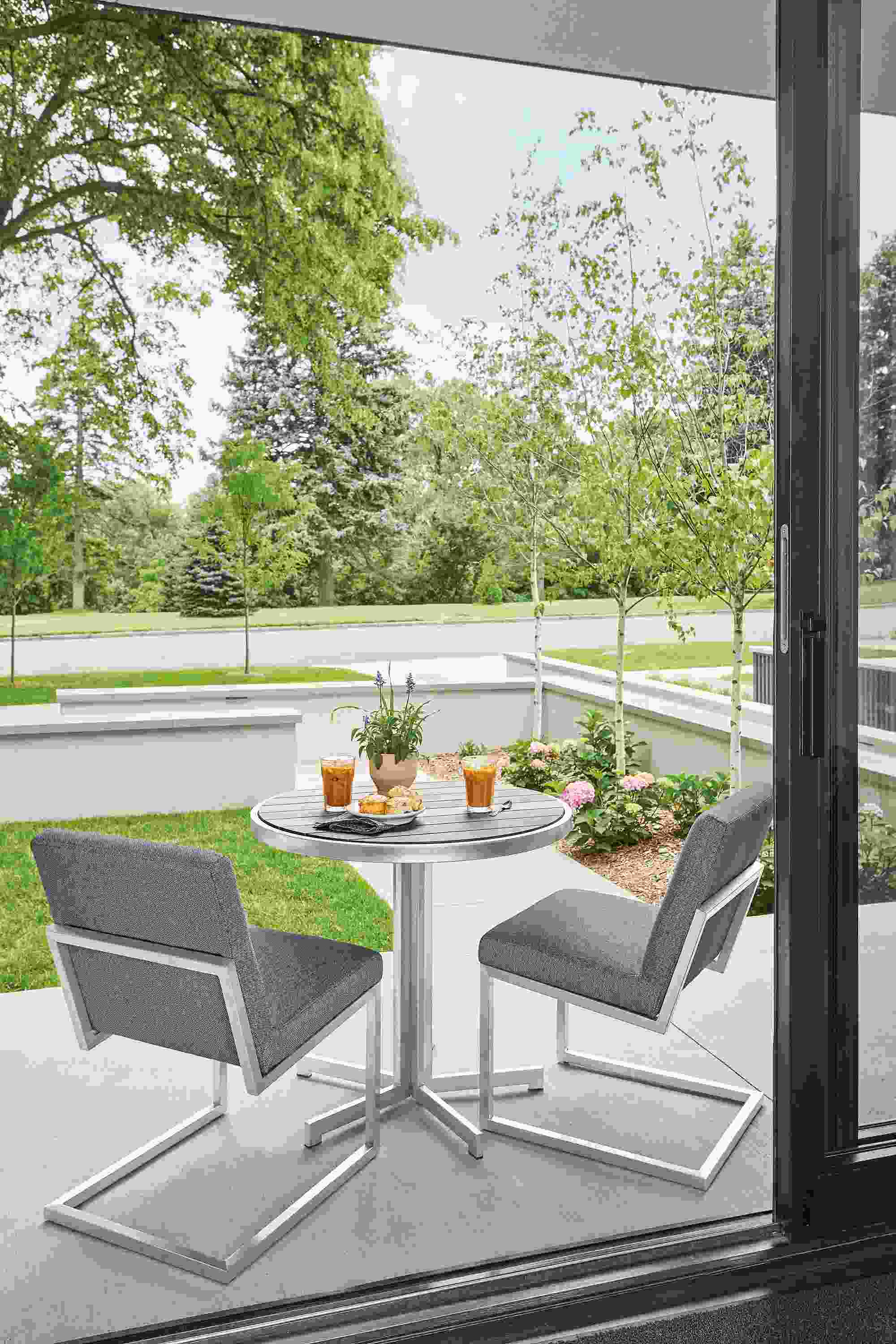 Outdoor patio with Finn side chairs in mist fabric and montego round table in aged ash.