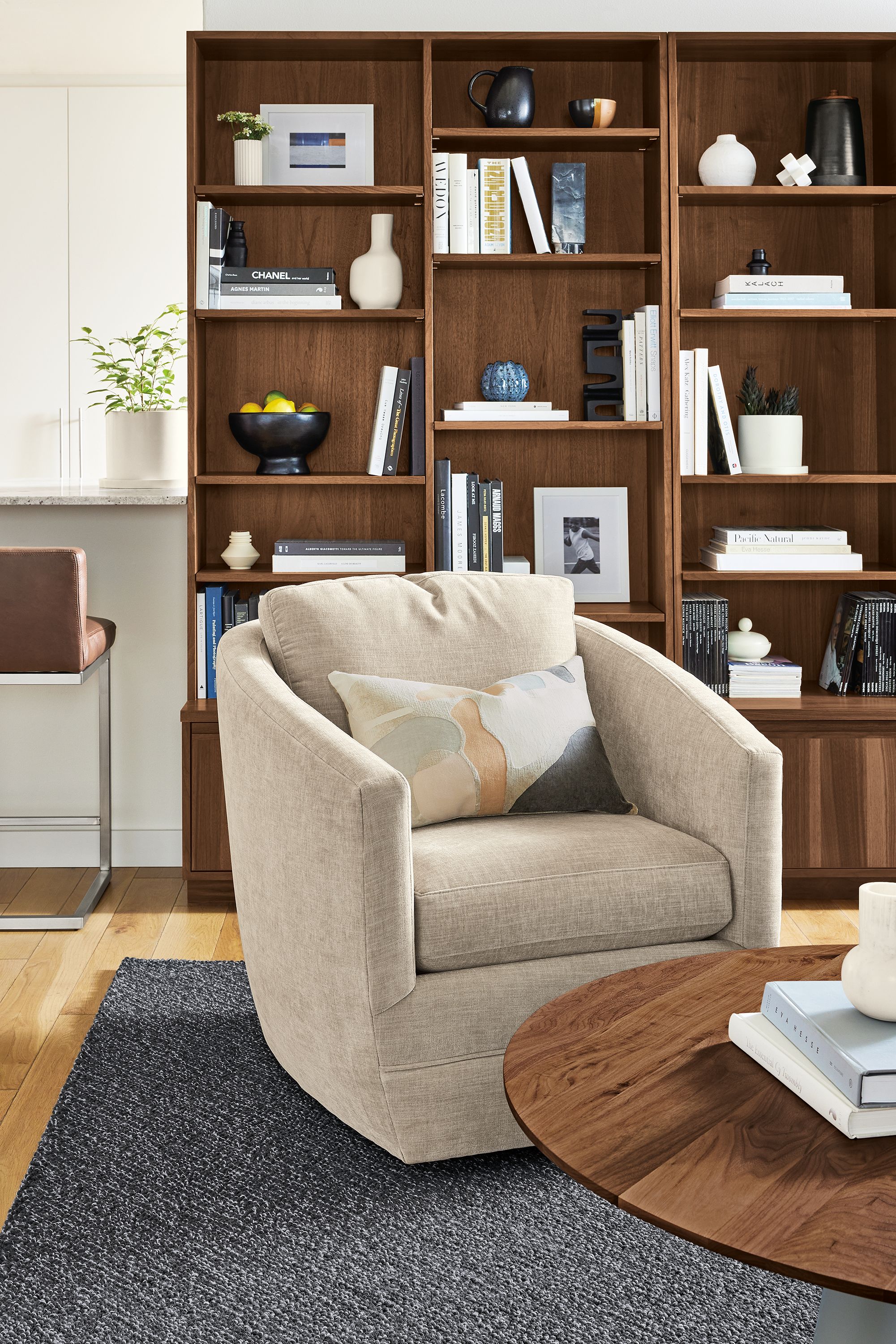 Living room with Ford swivel chair in Mori Oatmeal, Keaton bookcases in walnut and Decker coffee table in taupe and walnut.