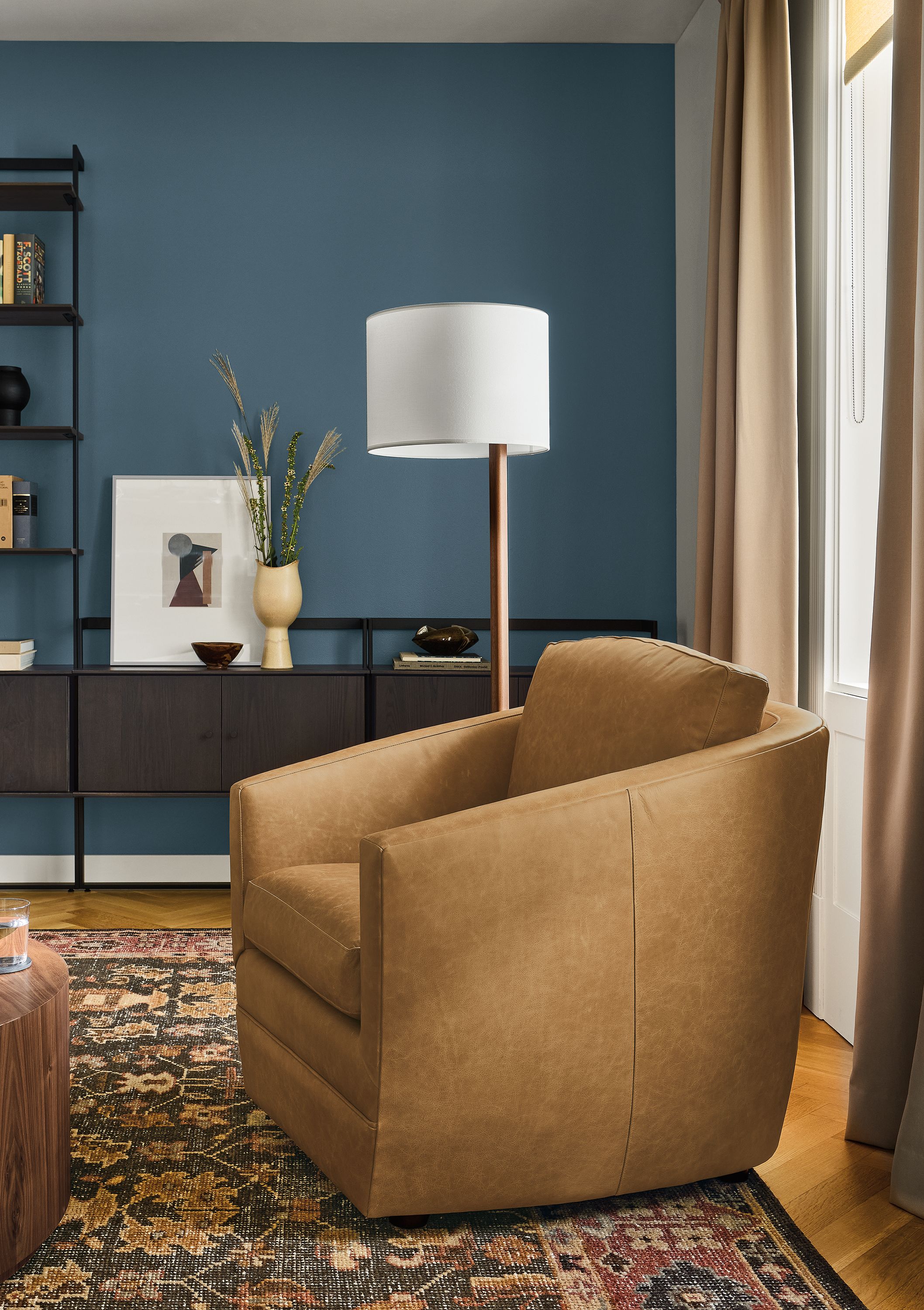 Living room with Ford chair in Palermo Camel leather, Beam bookcases in charcoal on ash and Tillia rug in brick.