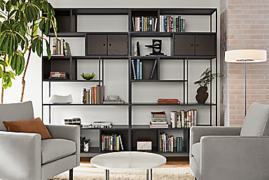 Living room setting with two Foshay 48-wide Bookcases in natural steel with charcoal Inserts, two Jasper 30-inch Chairs and Classic 27-Round Coffee Table.