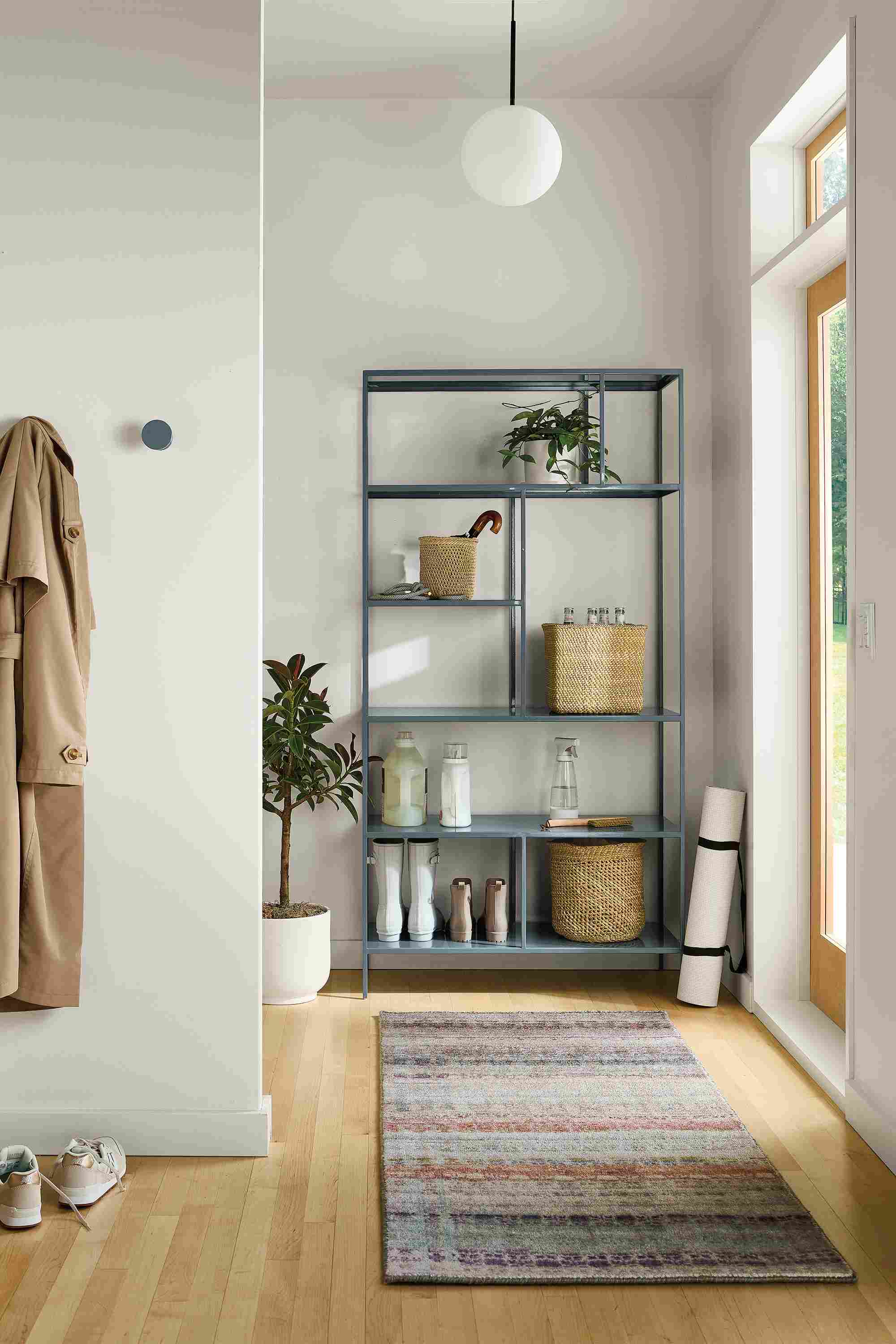 Entryway with Foshay 36-wide bookcase in cadet, Varun 2.5 by 6 rug in multicolor and Orbit pendant in matte black.