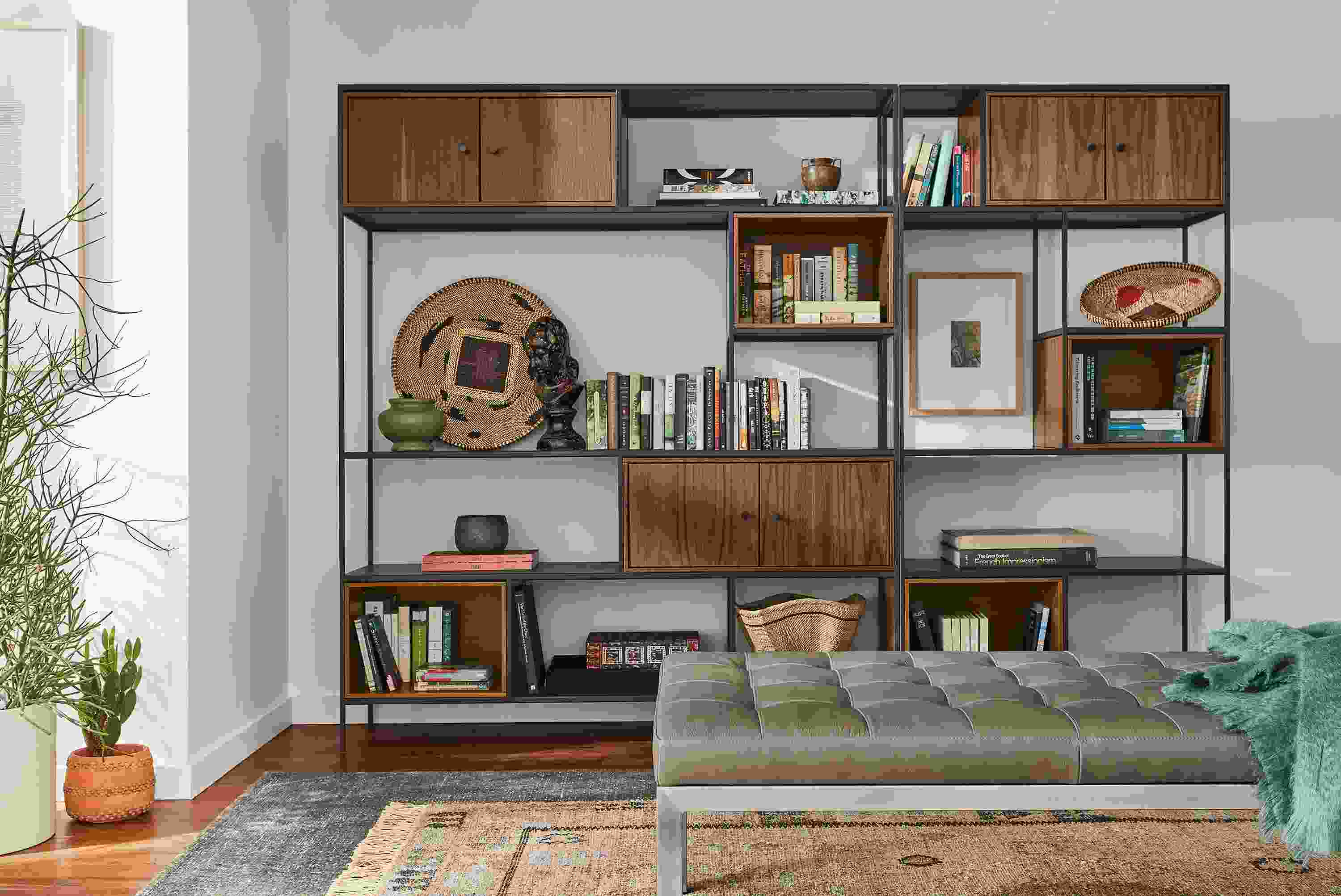 Living room with Foshay bookcase wall unit in natural steel with inserts in walnut and Ravella daybed in Pesaro Putty leather.