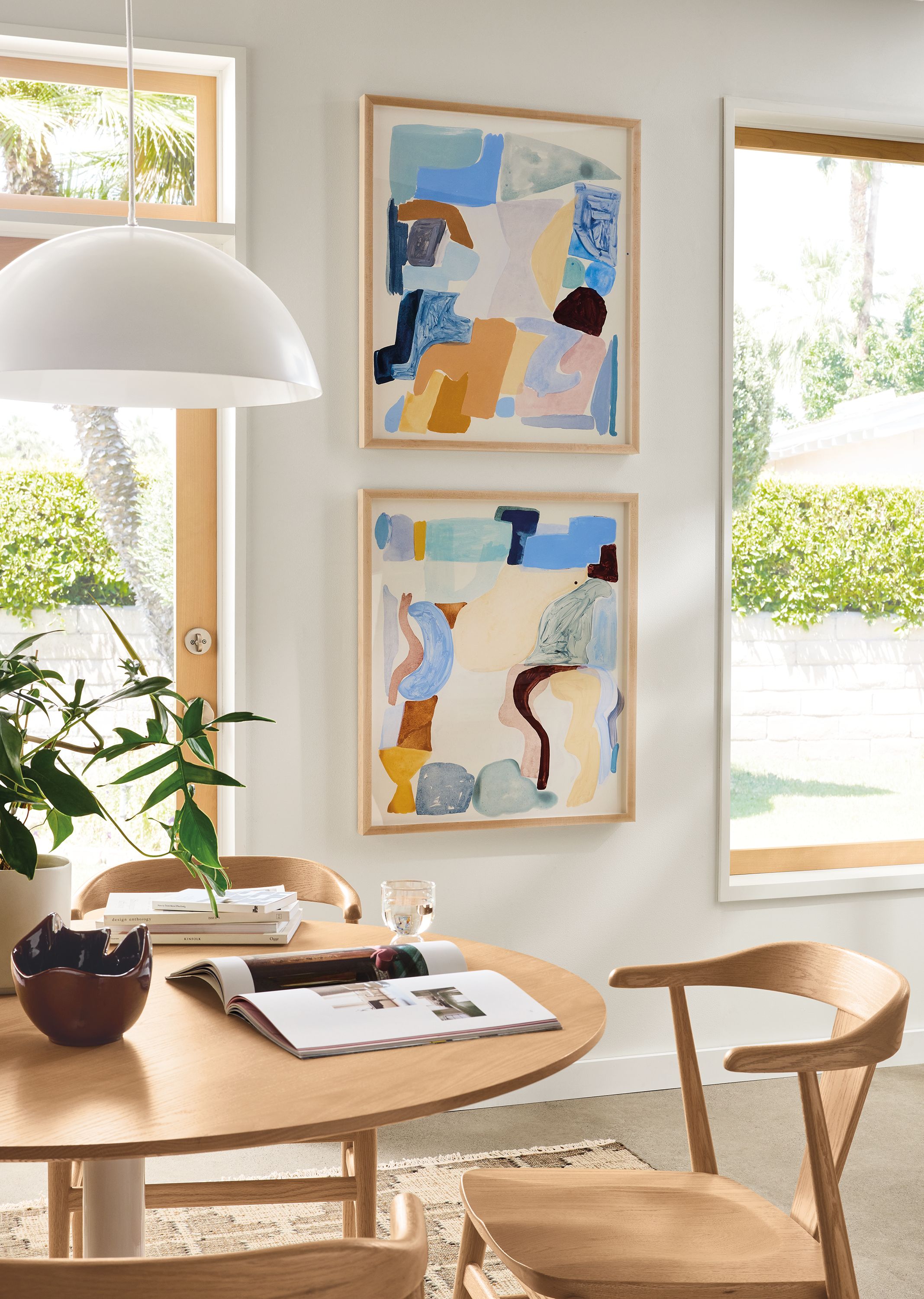 Dining area with 2 Jen Garrido wall art pieces with maple frames and an Aria table and Evan arm chairs in Rye on red oak.