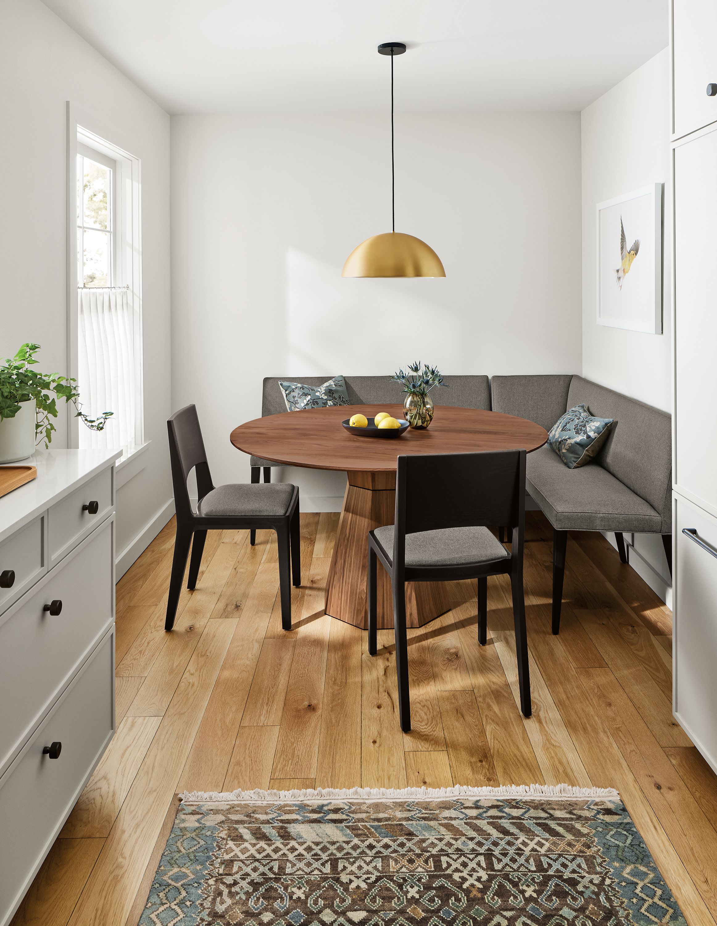 Kitchen nook with Glover 54-diameter round table in walnut and Ava right-corner banquette in Sumner Graphite.