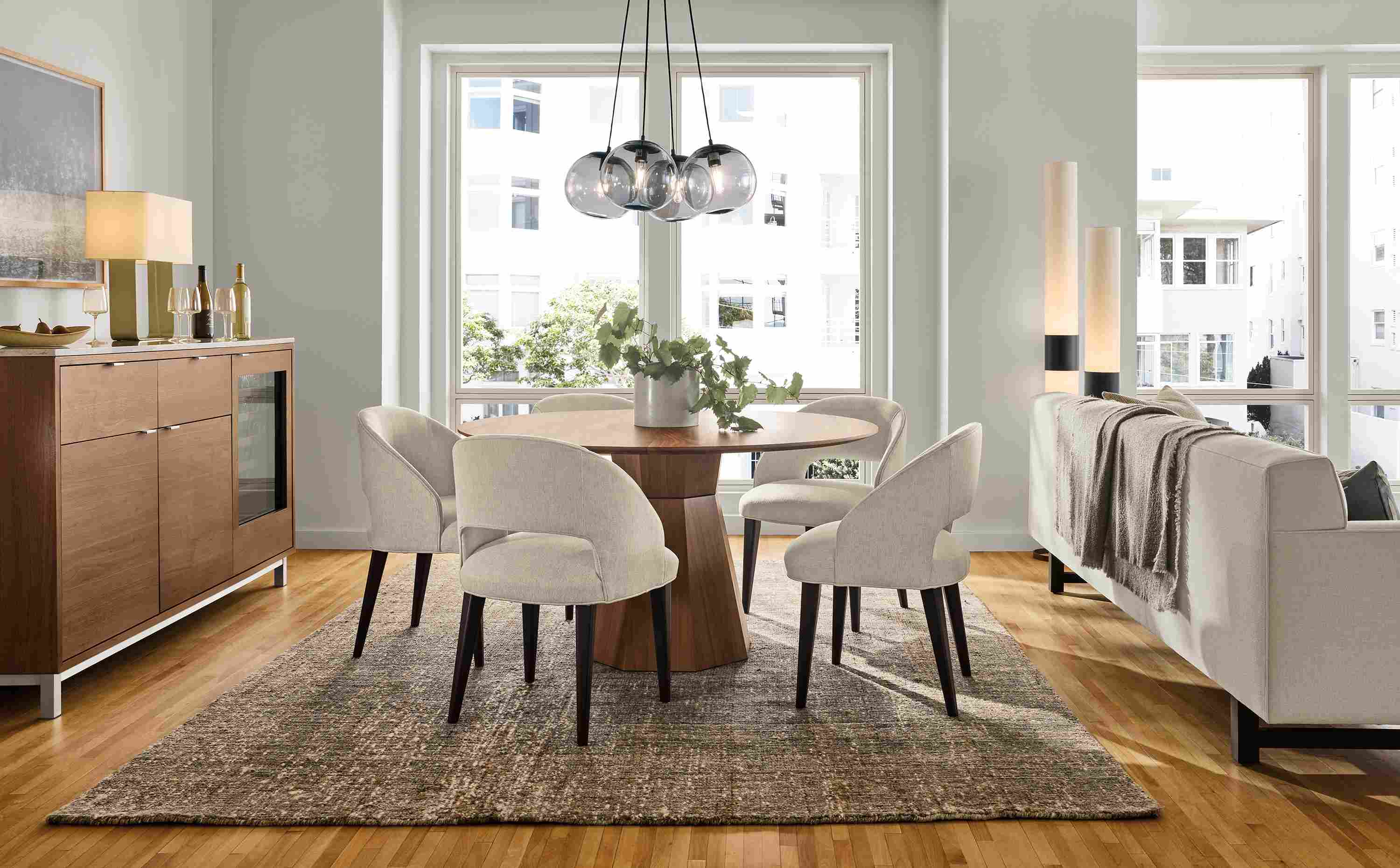 Great room with a Glover 54-diameter table in walnut, 5 Esme chairs in Sumner Linen and Ravani 8 by 10 rug in charcoal.