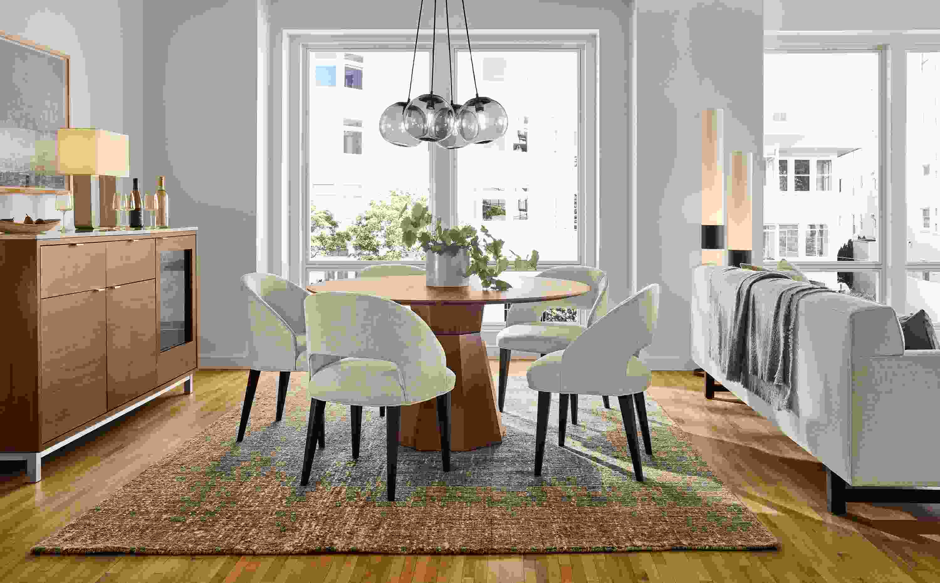 Great room with a Glover 54-diameter table in walnut, 5 Esme chairs in Sumner Linen and Ravani 8 by 10 rug in charcoal.