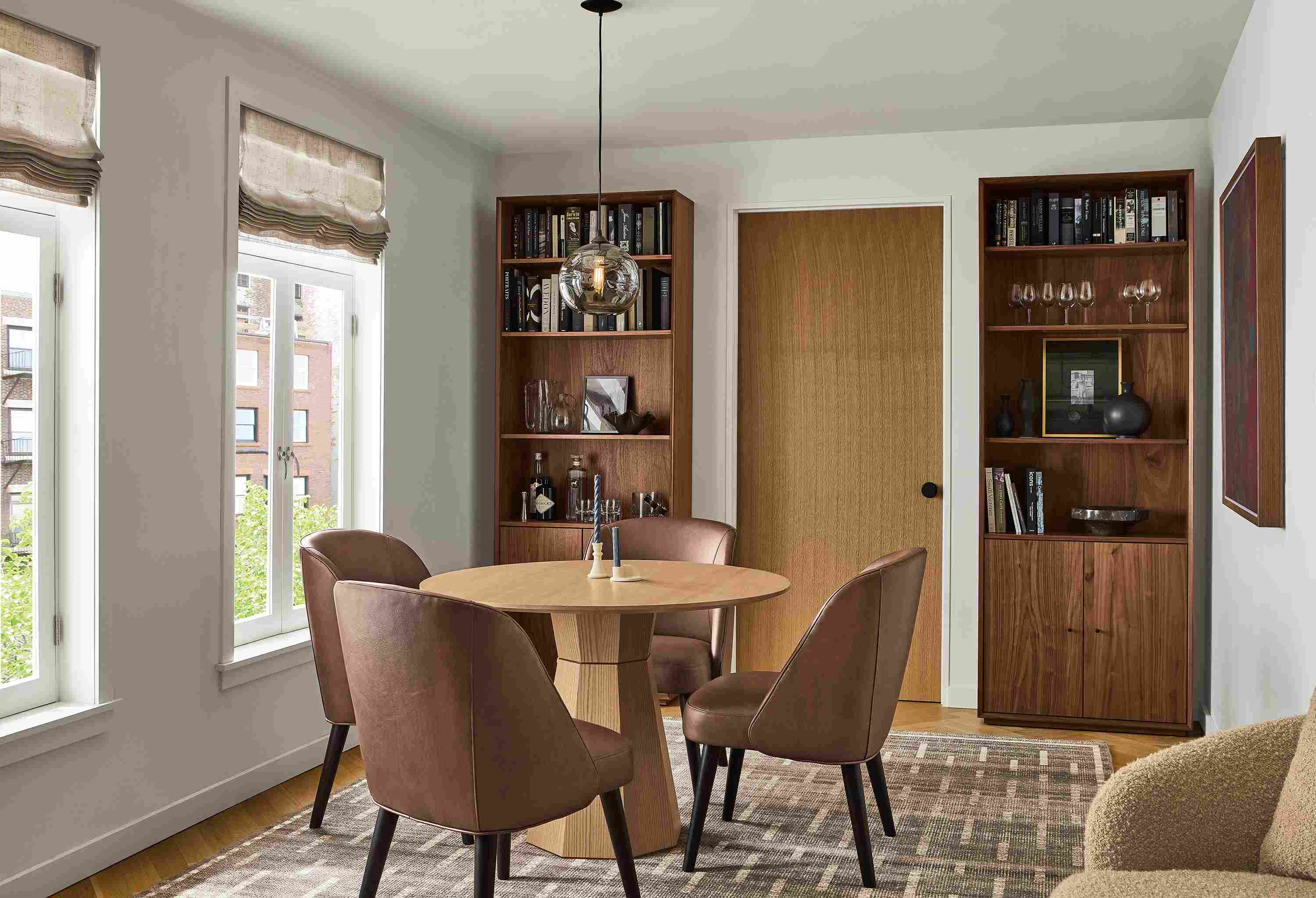 Dining room with Glover round table in rye on red oak, Cora side chairs in Laino Cognac and Baran 8 by 10 rug in grey.
