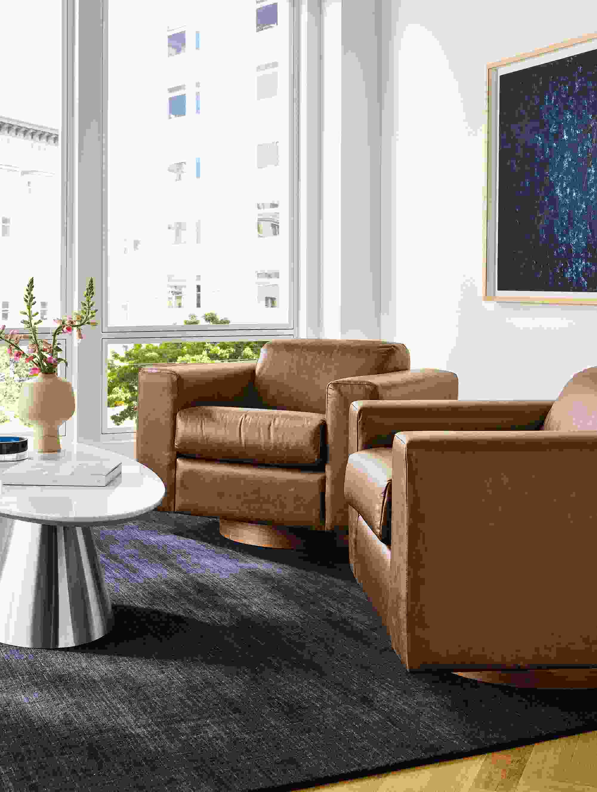 Living room with 2 Harmon swivel chairs in Palermo Bourbon leather and Nomad 9 by 12 rug in black.