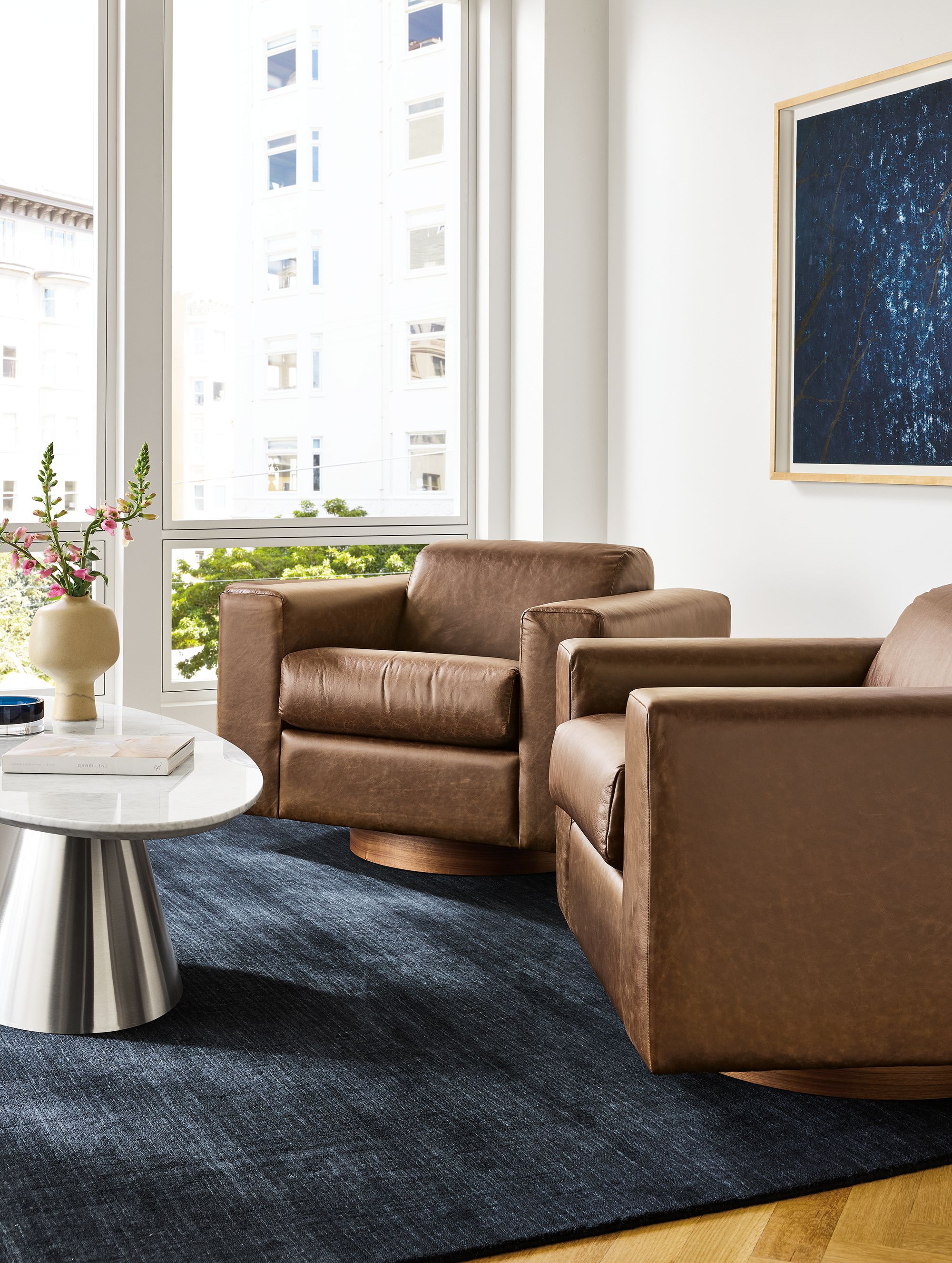 Living room with 2 Harmon swivel chairs in Palermo Bourbon leather and Nomad 9 by 12 rug in black.