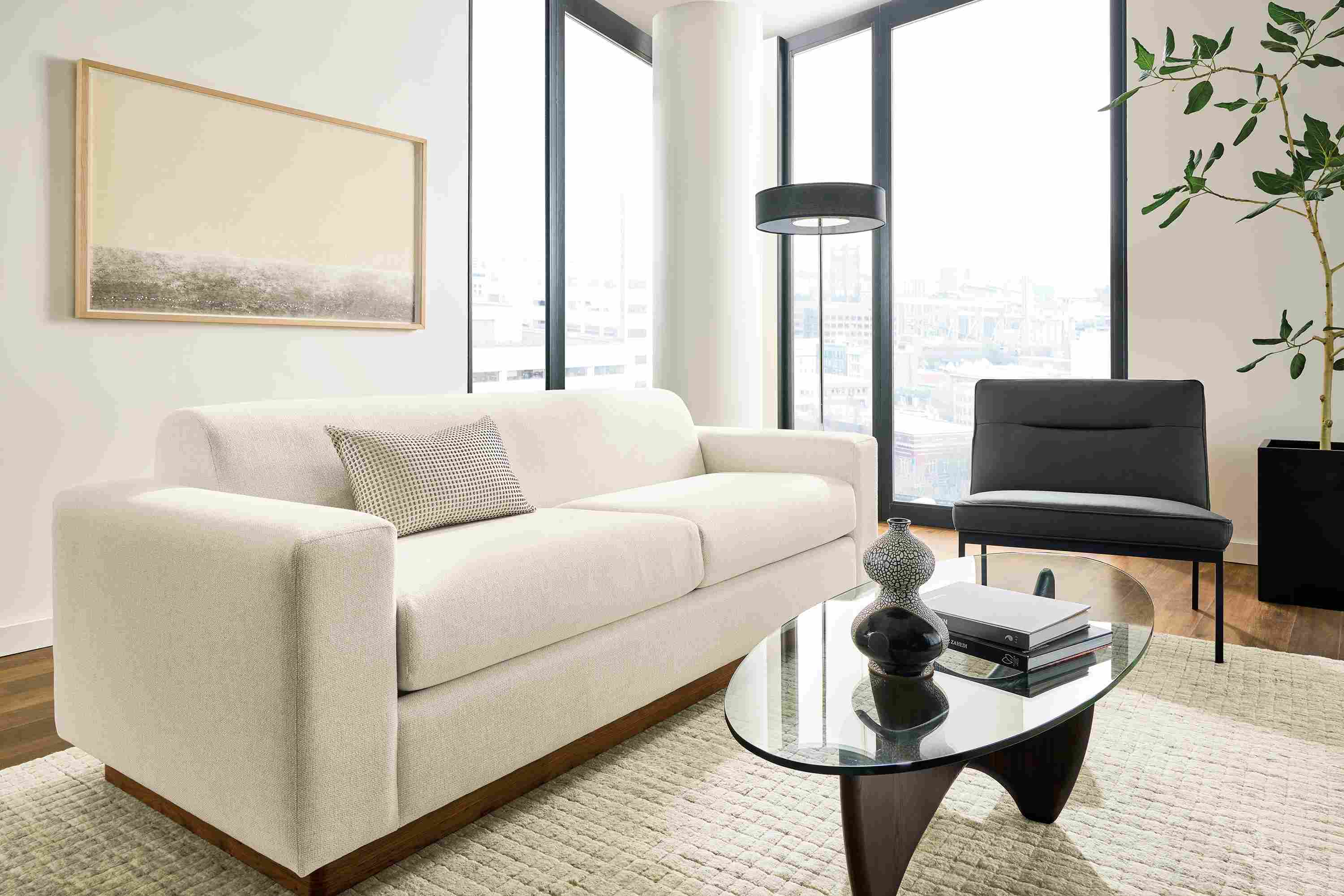 Living room with Harmon sofa in Tepic Ivory, Lisbon chair in Laino black leather and Safira rug in grey.