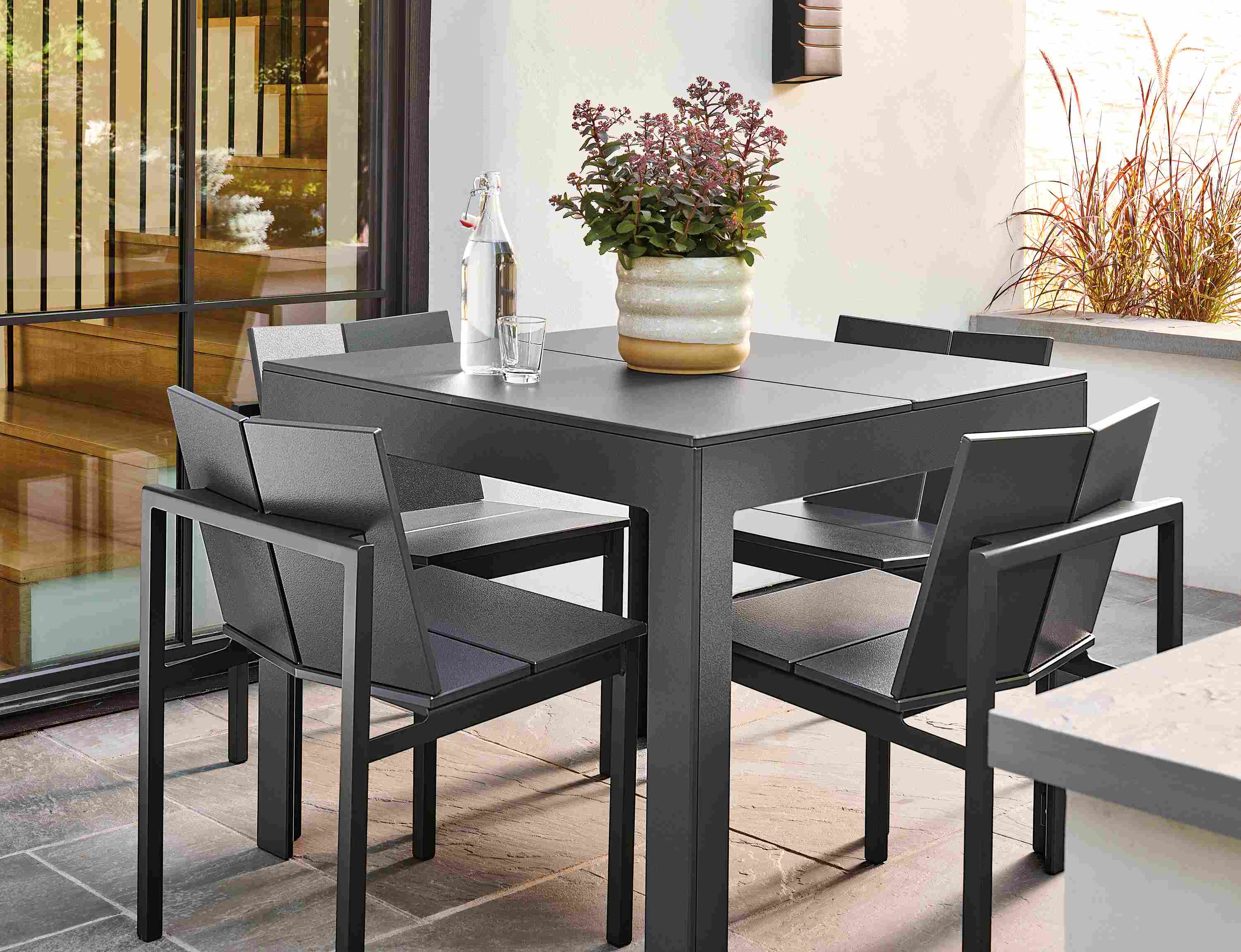 Outdoor space with Henry table and Mattix side chairs in grey and an elias planter in natural.