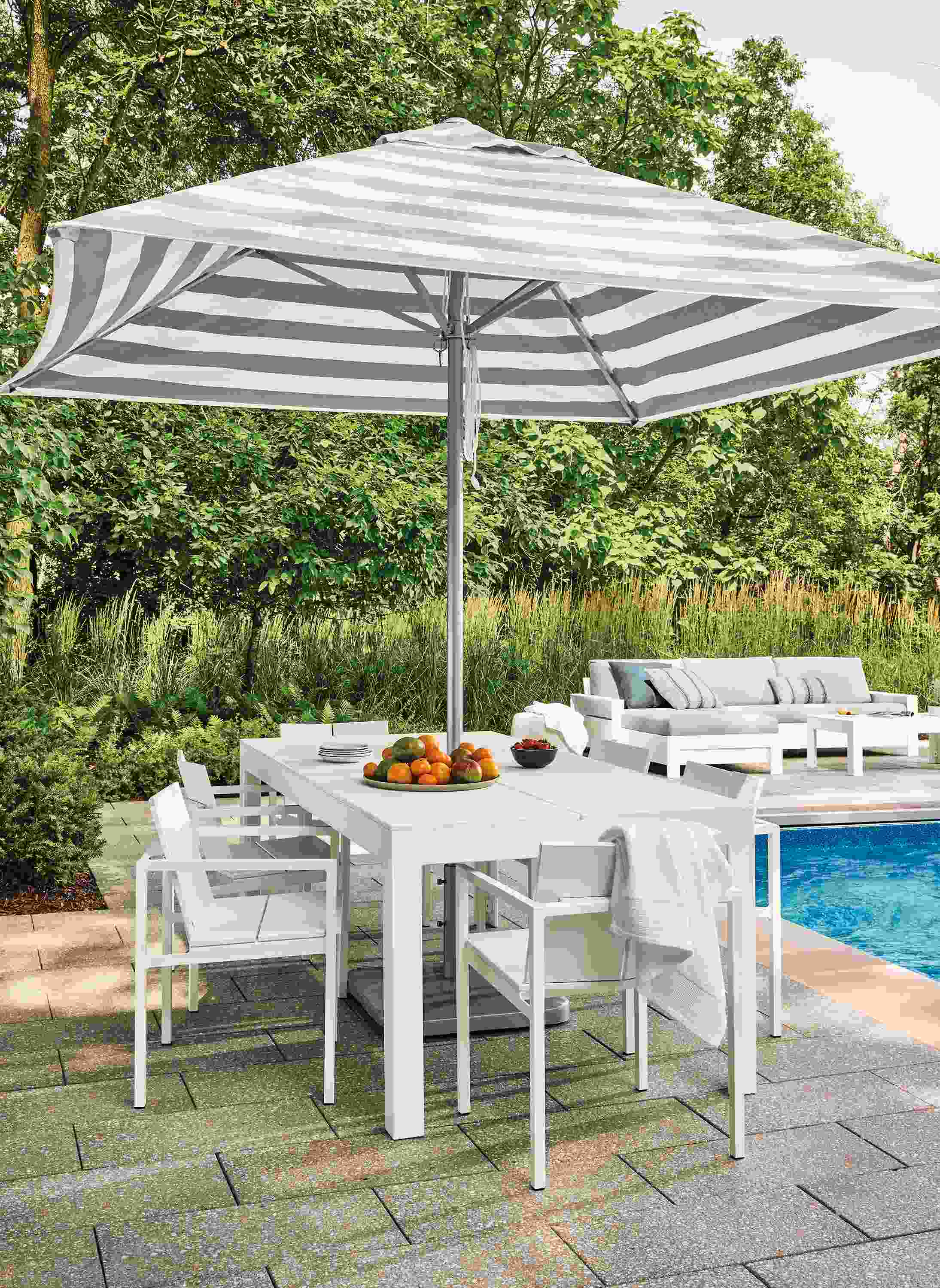 Pool patio with Henry table in white HDPE, 6 Mattix arm chairs in white HDPE and Pacifia umbrella in Jace stripe putty.