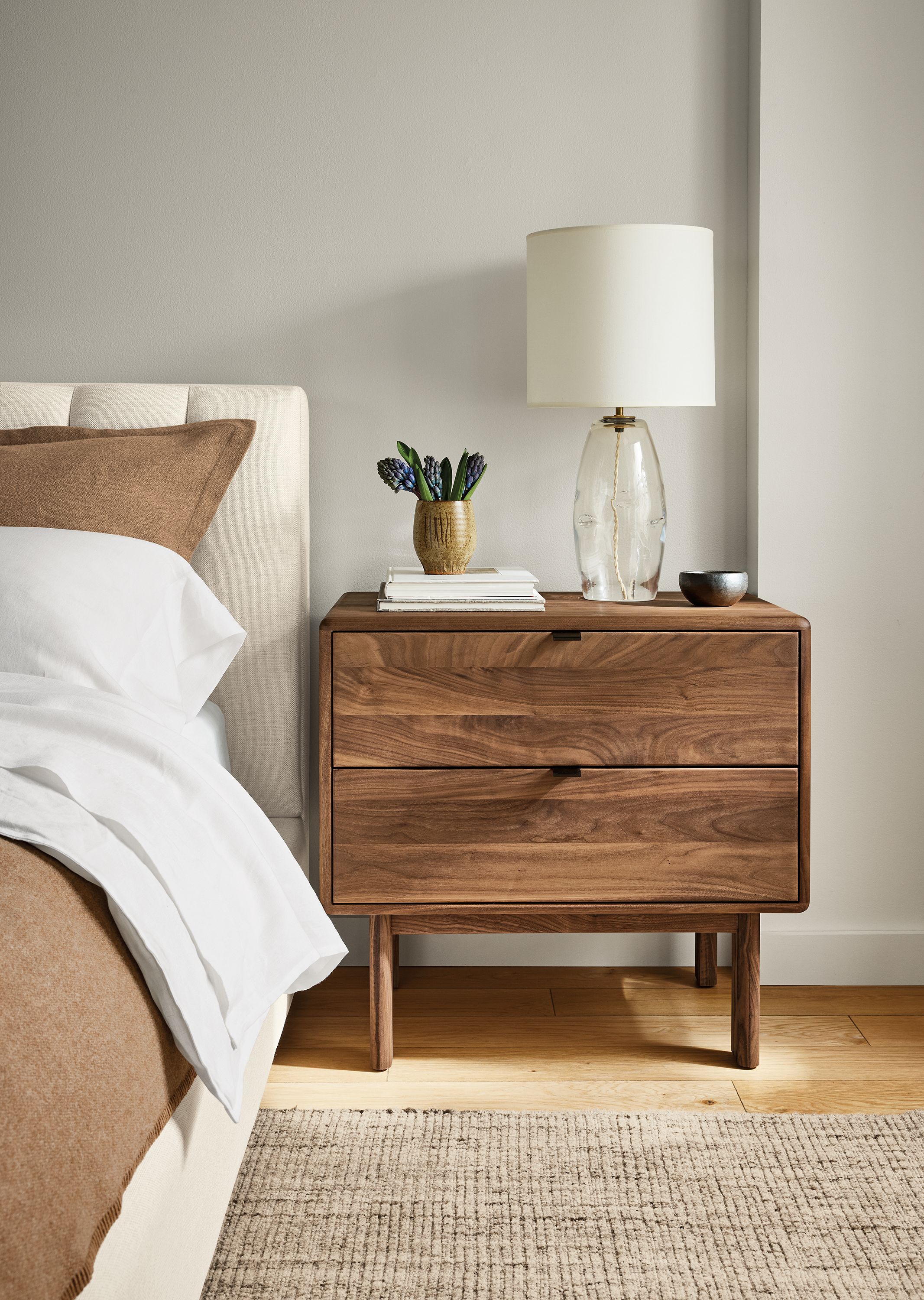 Bedroom with detail of Hensley 2-drawer nightstand in walnut and Artis rug in stone.
