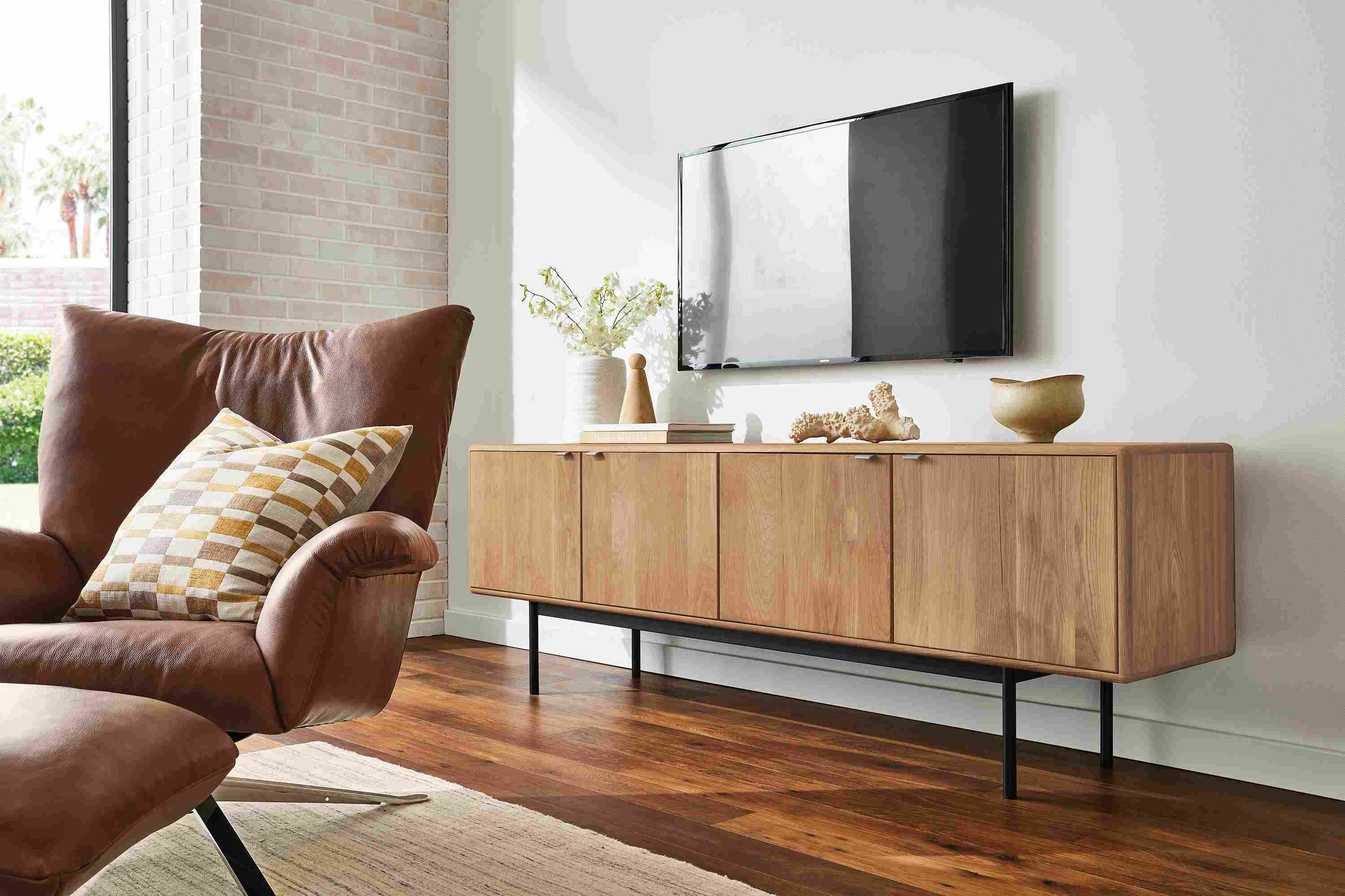 Living room with hensley media cabinet in rye on red oak and paris swivel chair in lecco cognac.