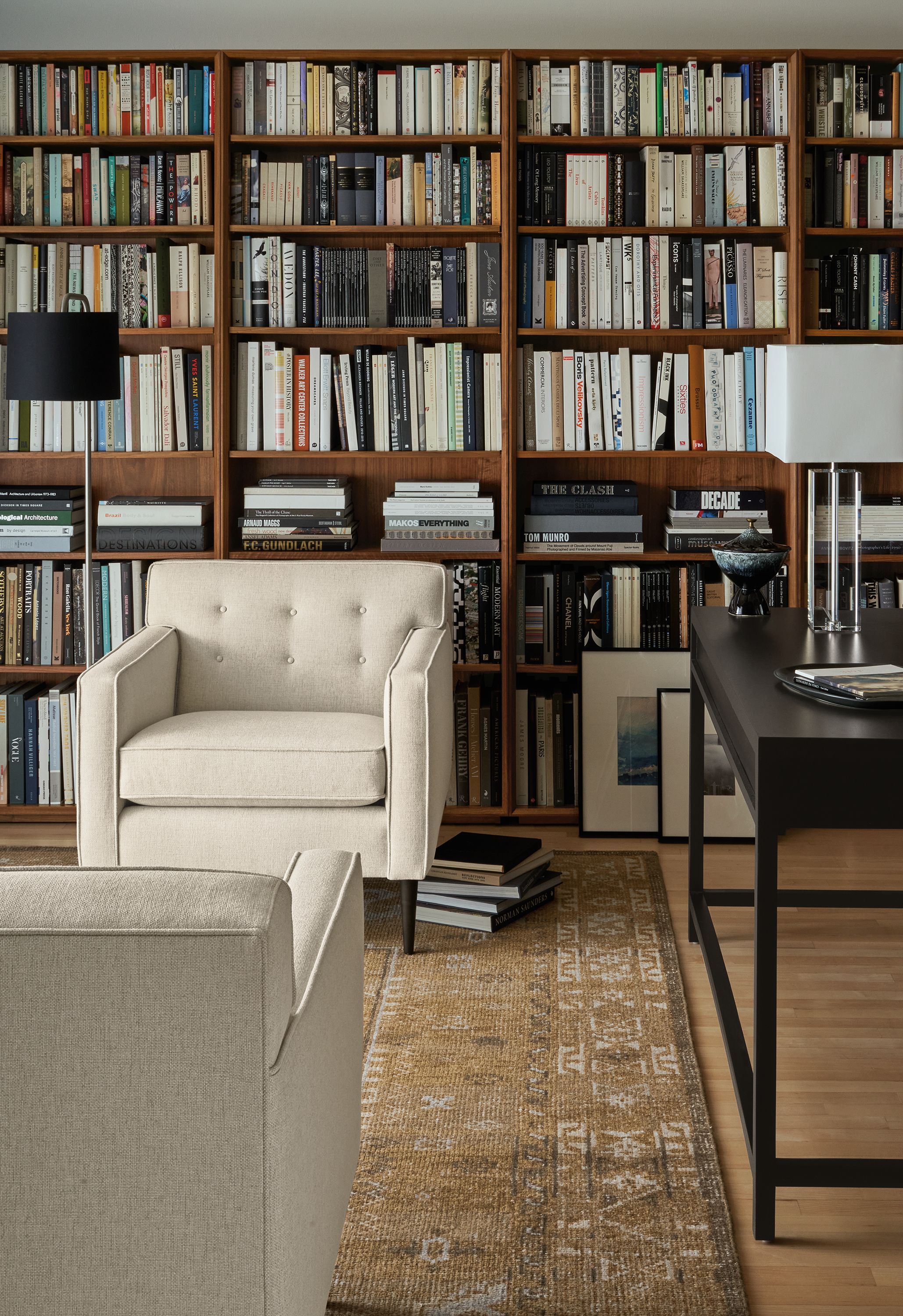 Living room library with 2 Holmes 30-inch chairs in Sumner Ivory, Rollins bookcases in walnut and Darrah rug in camel.