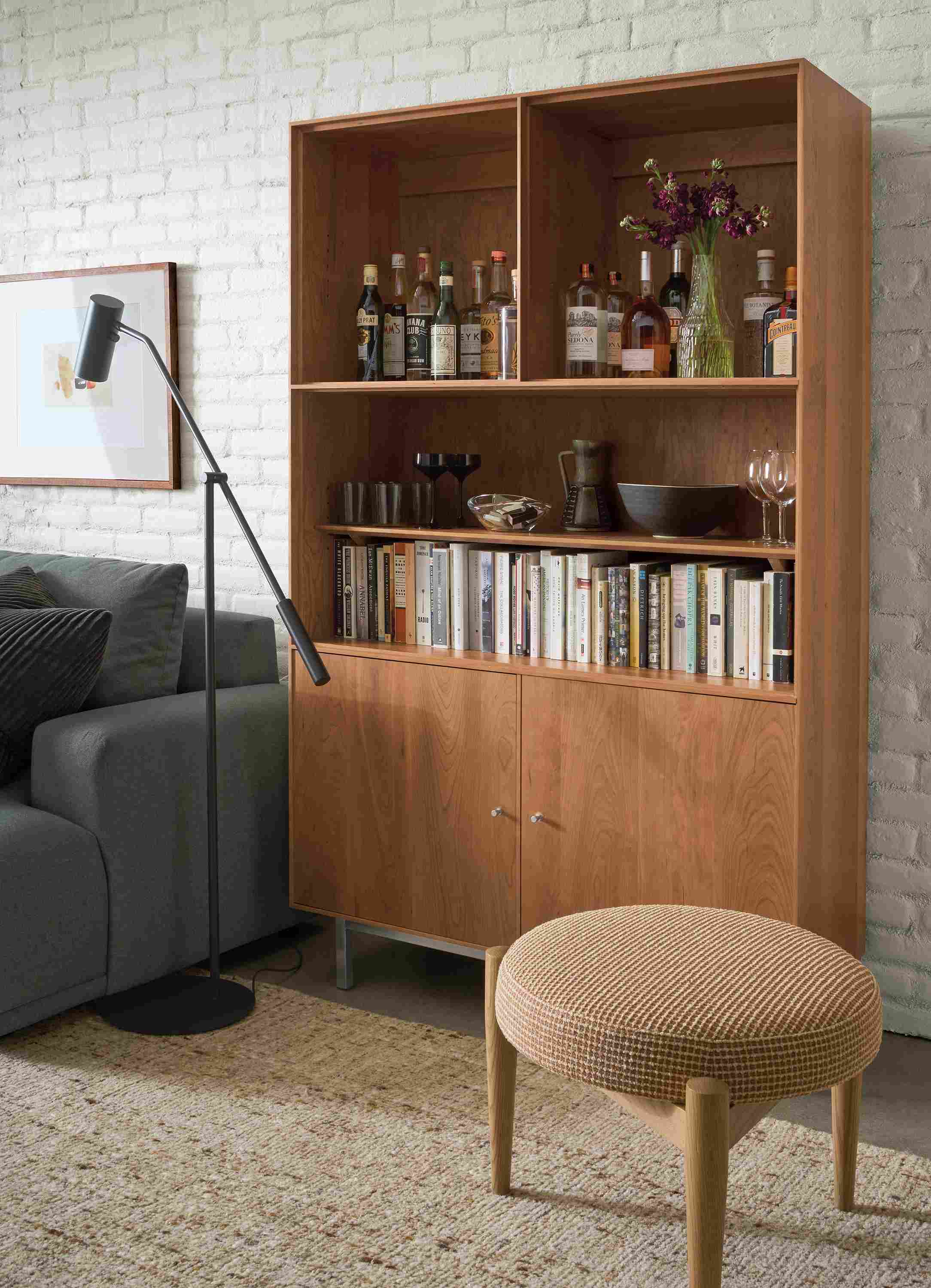Living room with detail of Hudson custom 6-insert cabinet in cherry and Murphy round stool in Dorsa Clay.
