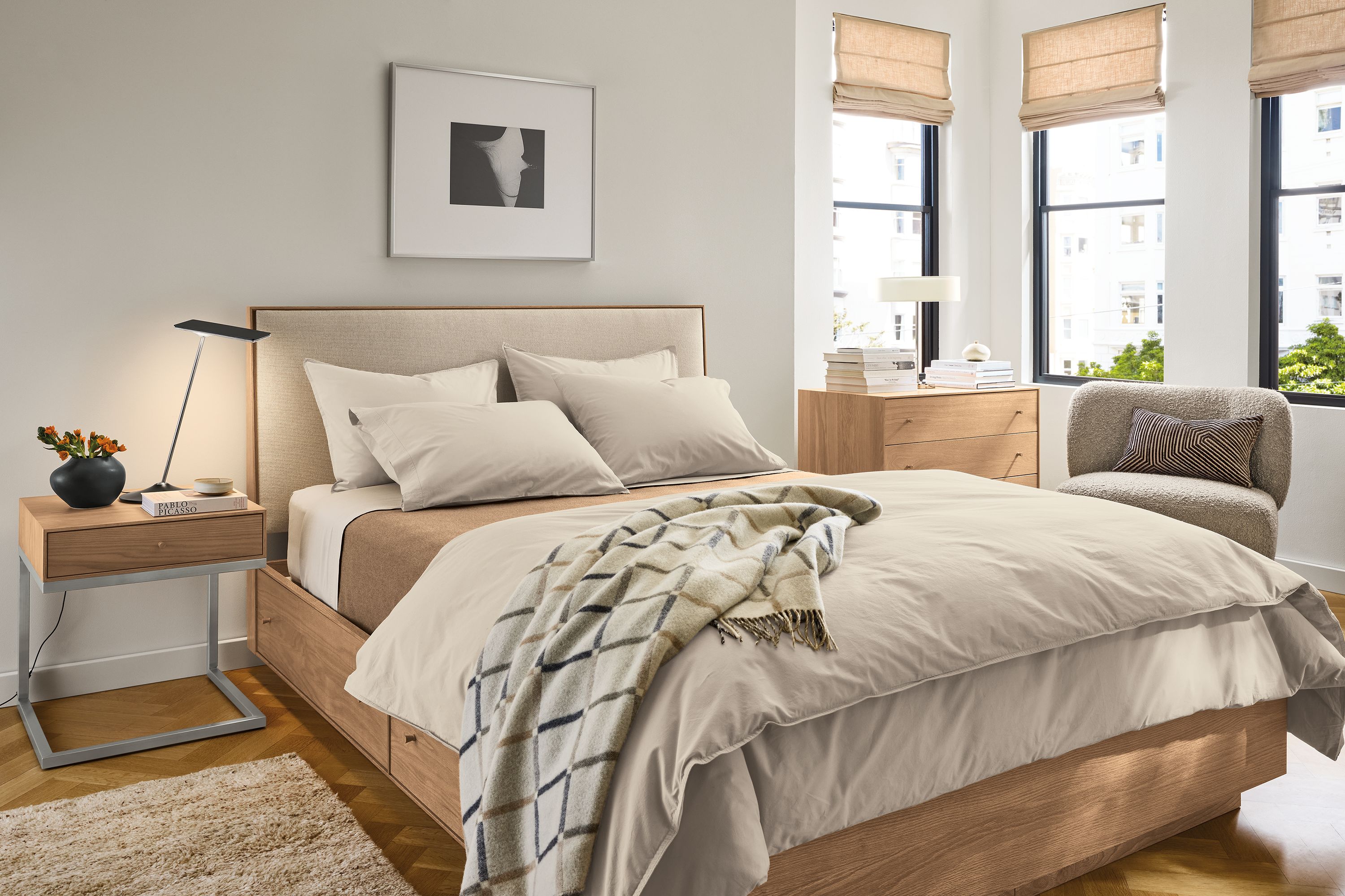 Sunny bedroom with Hudson storage bed, nightstand and dresser in rye on red oak and Rory swivel chair in Dornick Otter.