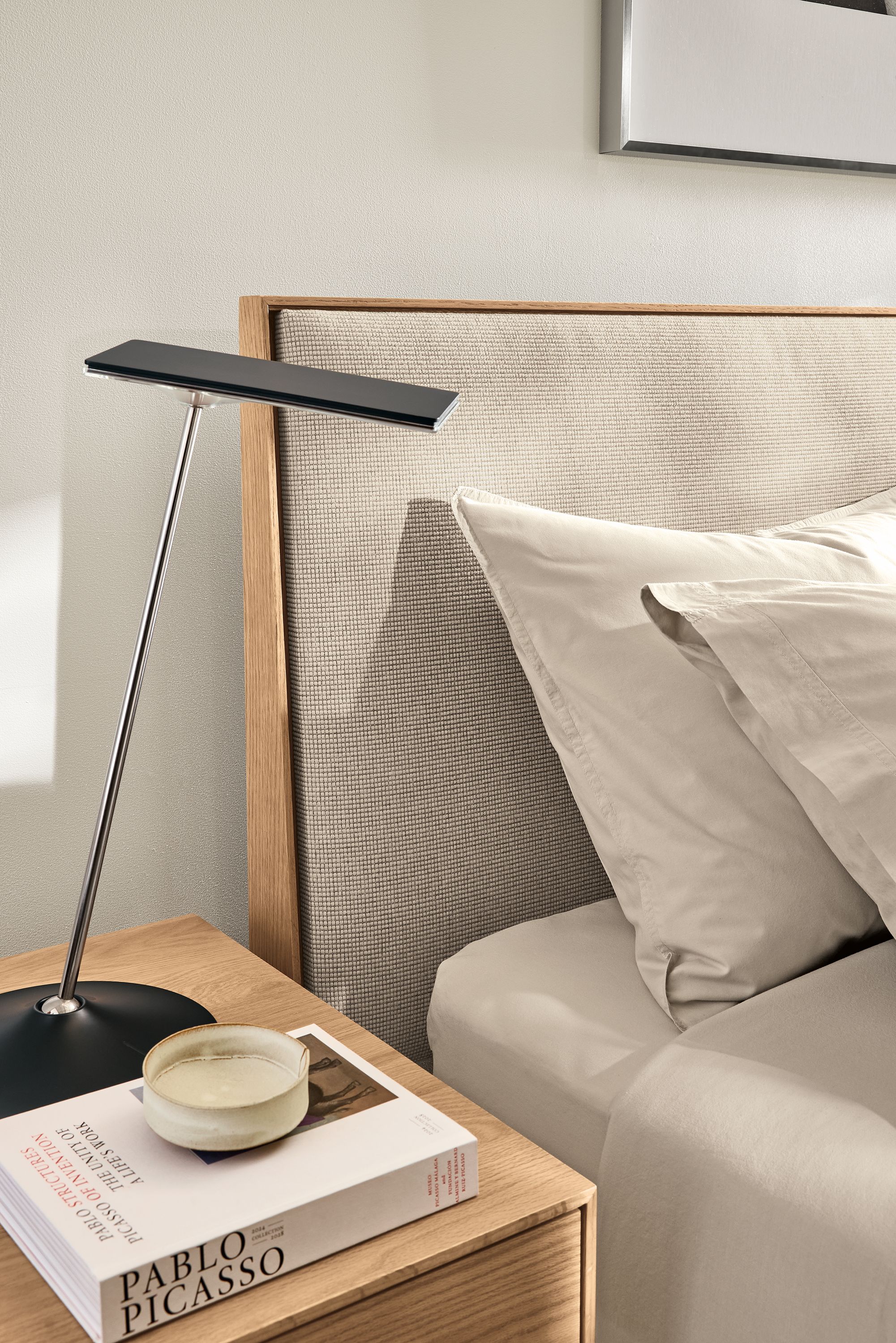 Bedroom with detail of Hudson storage bed in kesler oatmeal and rye on red oak and a Horizon LED table lamp in black.