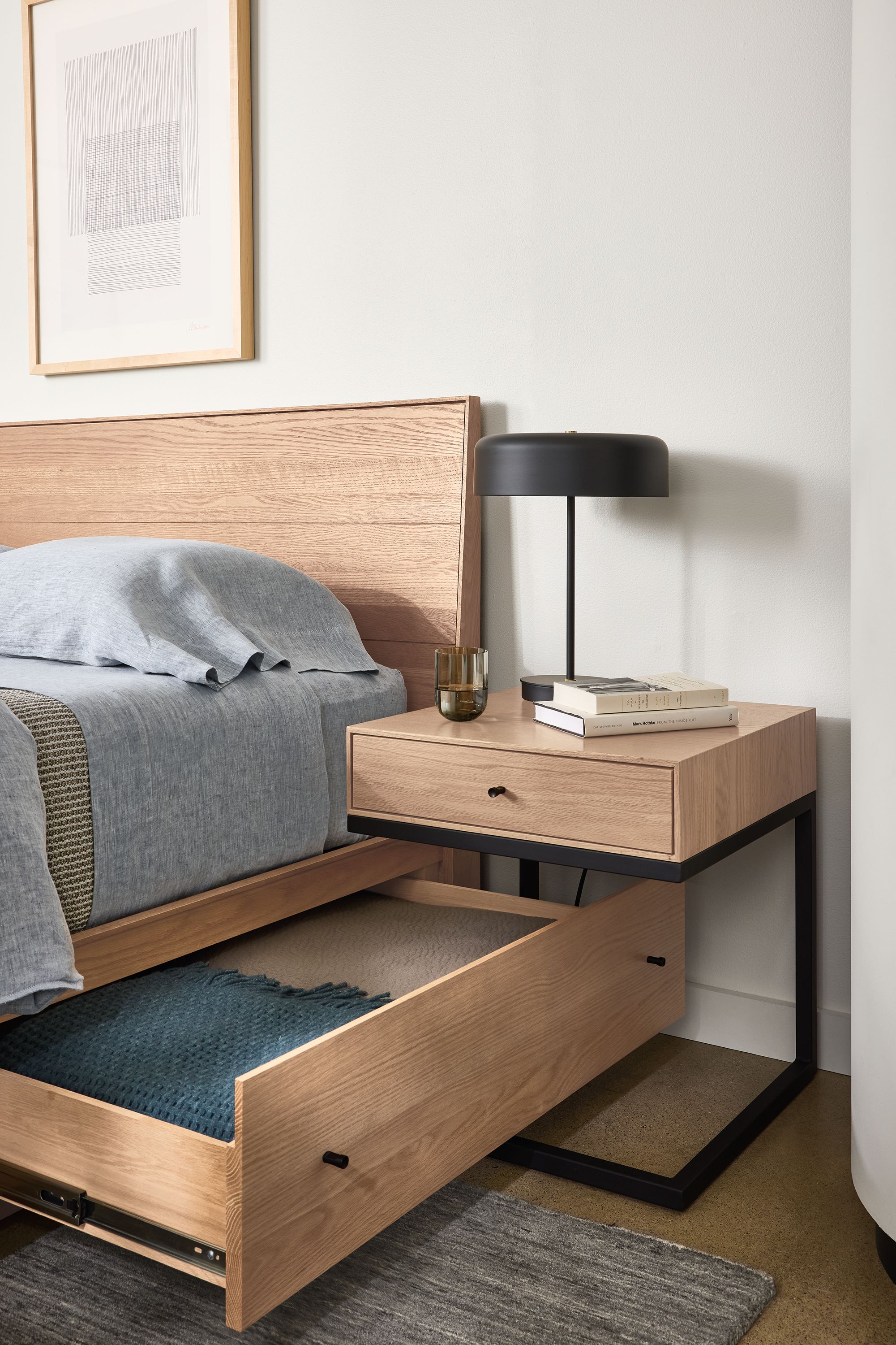 Bedroom showing open drawer on Hudson queen storage bed and Hudson one-drawer C-table in rye on red oak.
