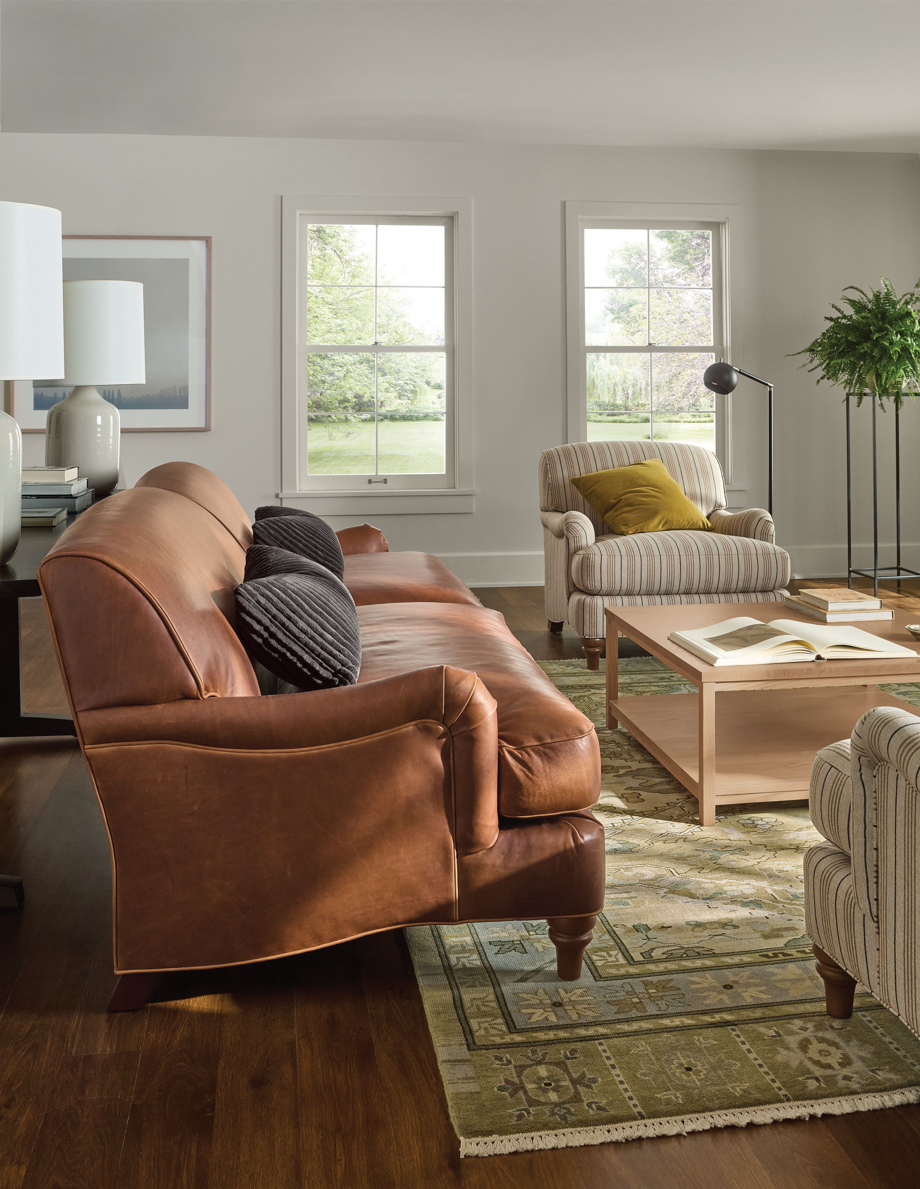 Living room with side view of a Humphrey 92-wide sofa in Sarto Cognac leather and Clark coffee table in Red oak with rye stain.