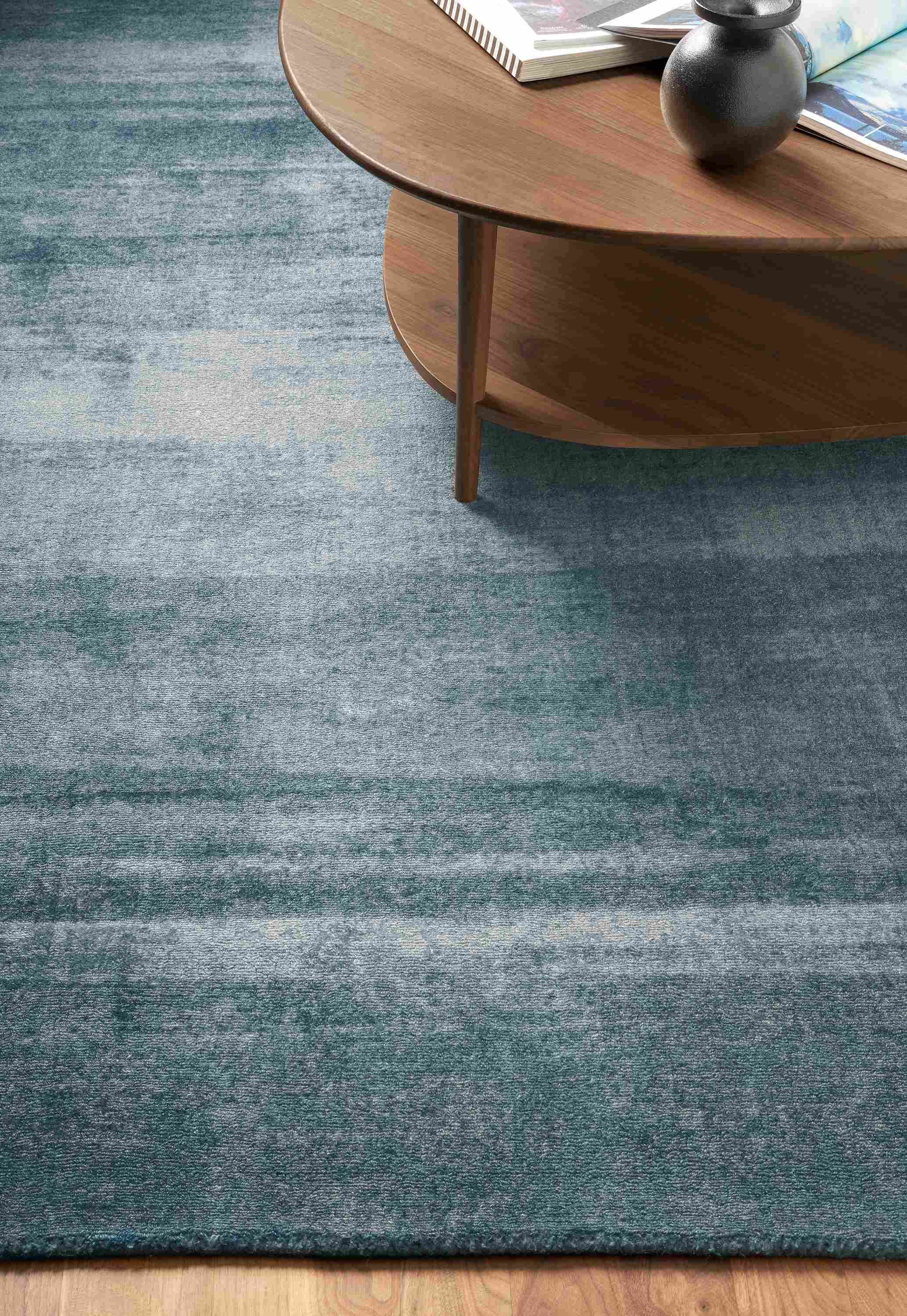 Detail of Impression rug in Blue in living room with Gibson coffee table in walnut.