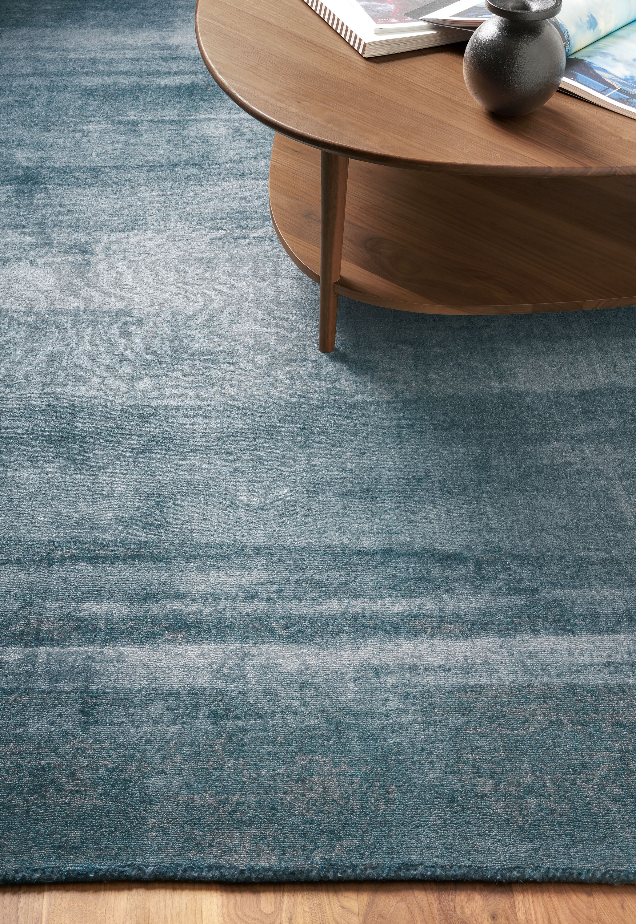 Detail of Impression rug in Blue in living room with Gibson coffee table in walnut.