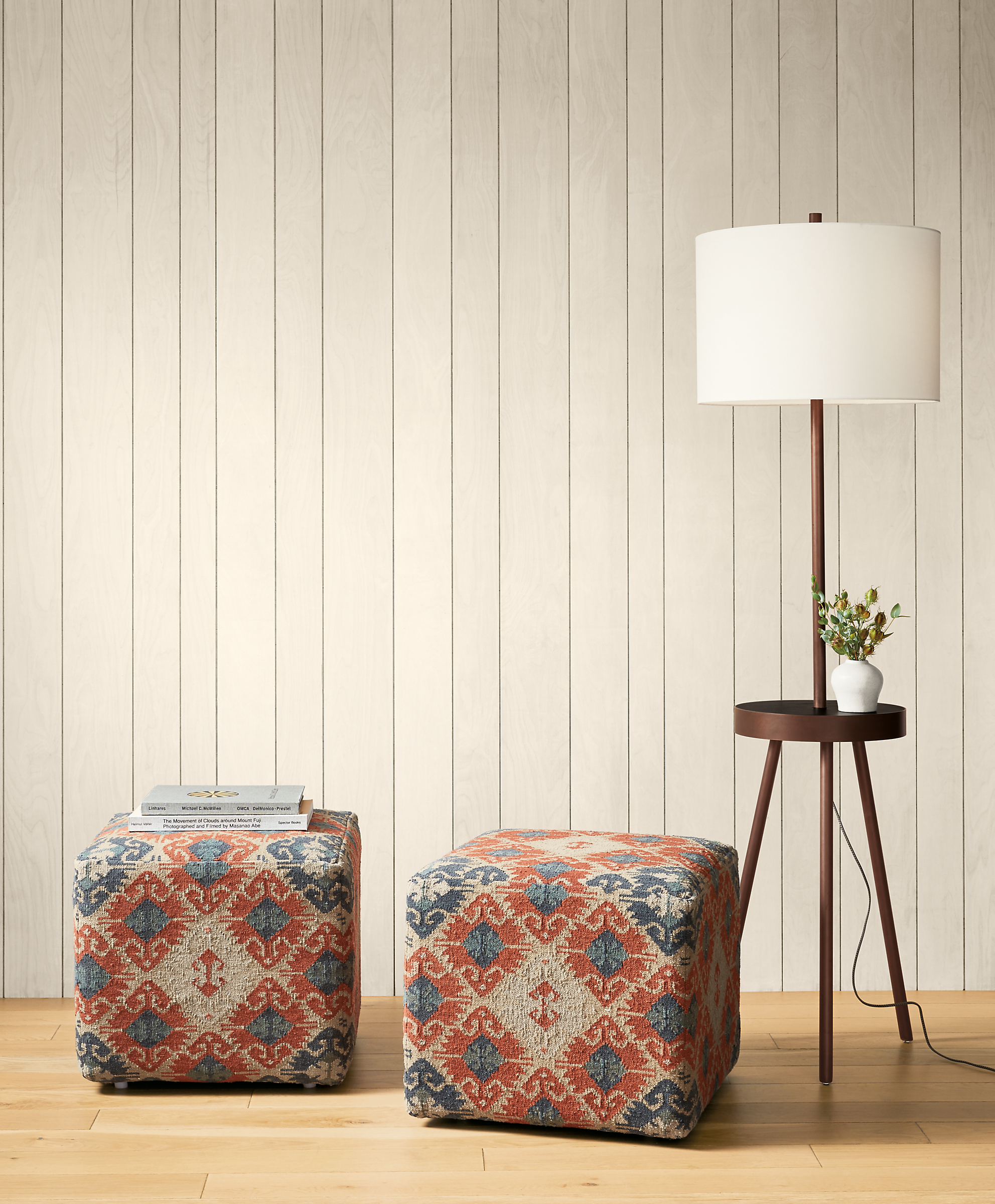 Detail of 2 Indira square ottomans in Paprika beside Winford floor lamp.