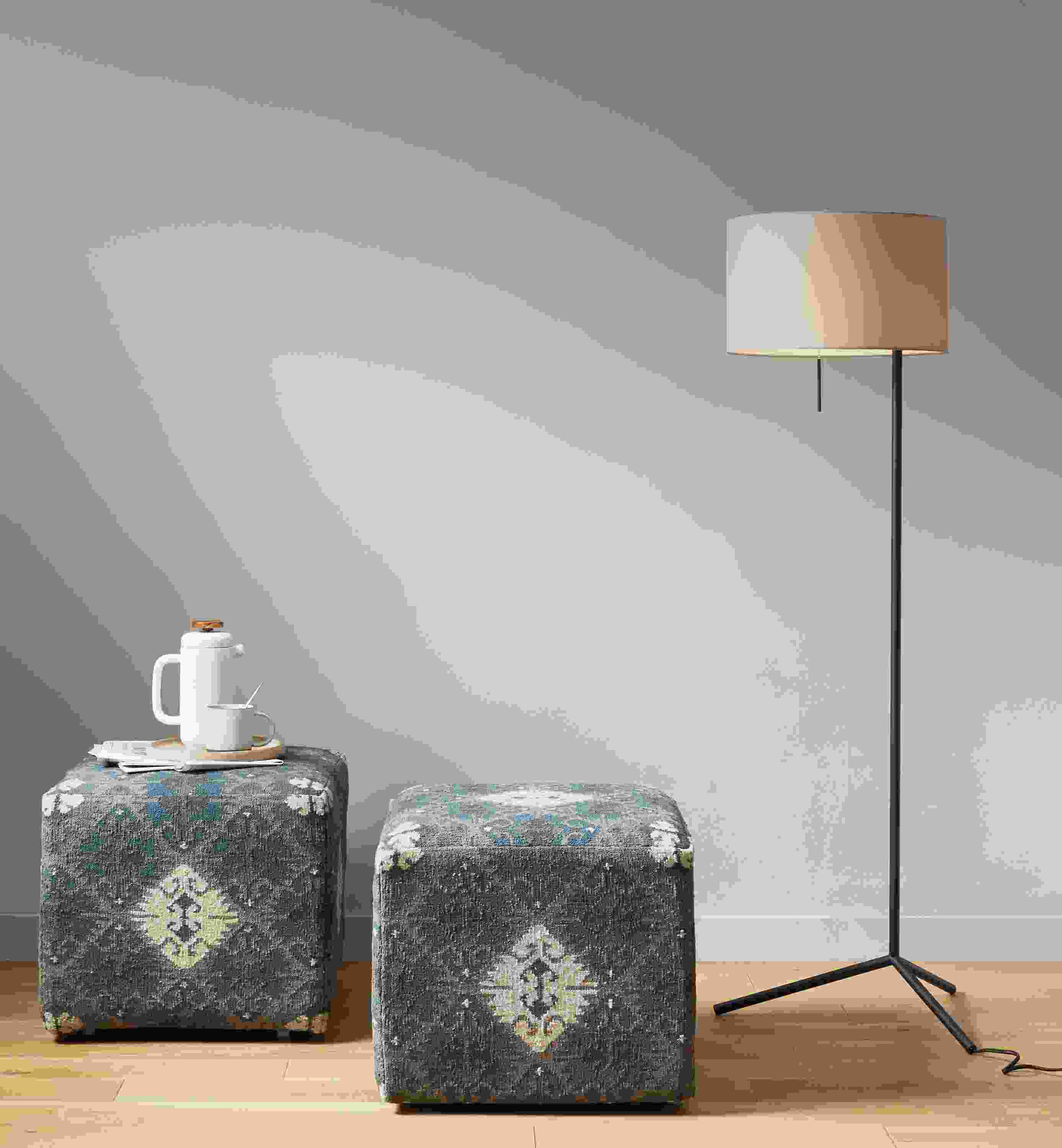 Detail of 2 Indira square ottomans in Blue beside Crane floor lamp.