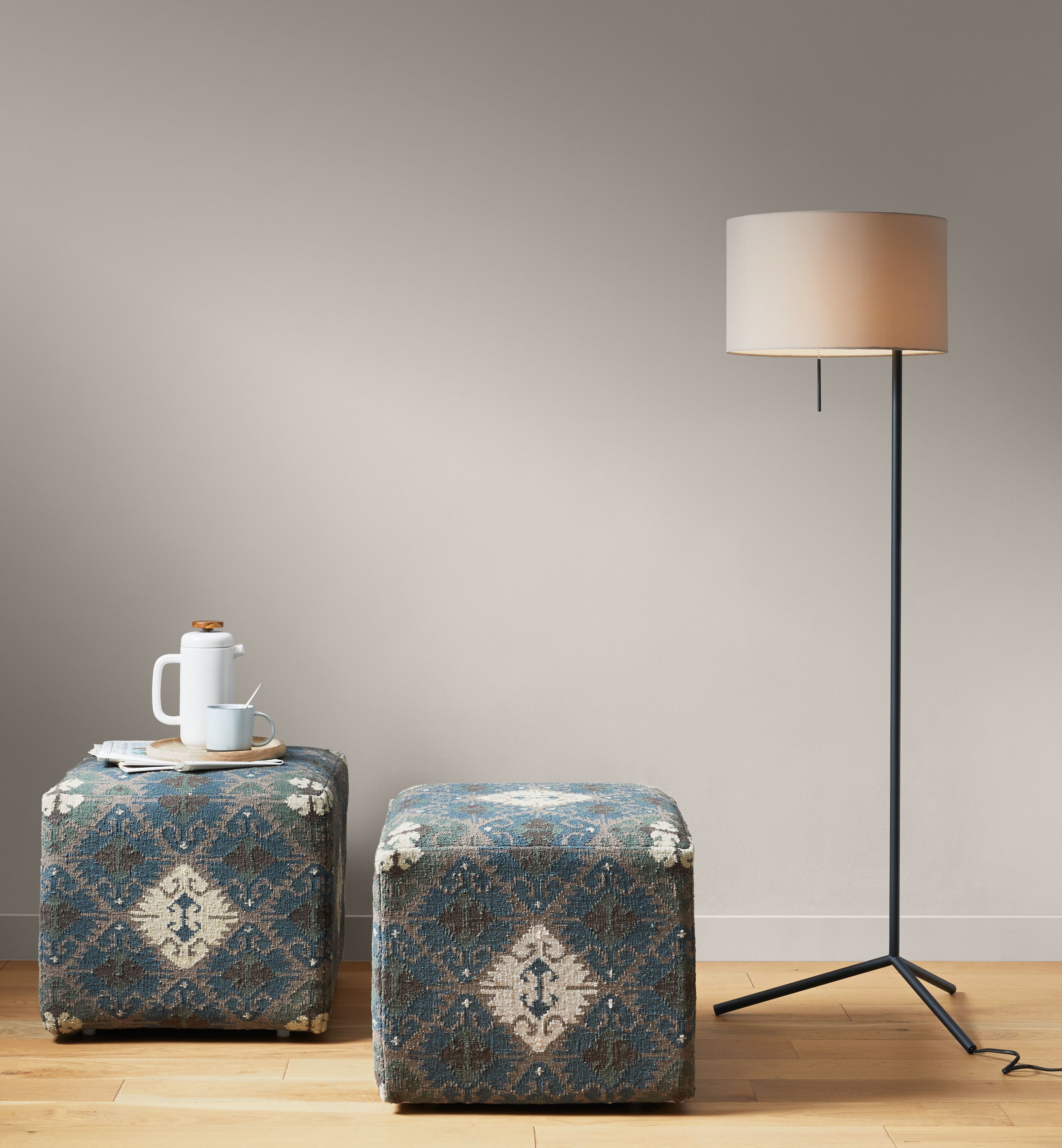 Detail of 2 Indira square ottomans in Blue beside Crane floor lamp.