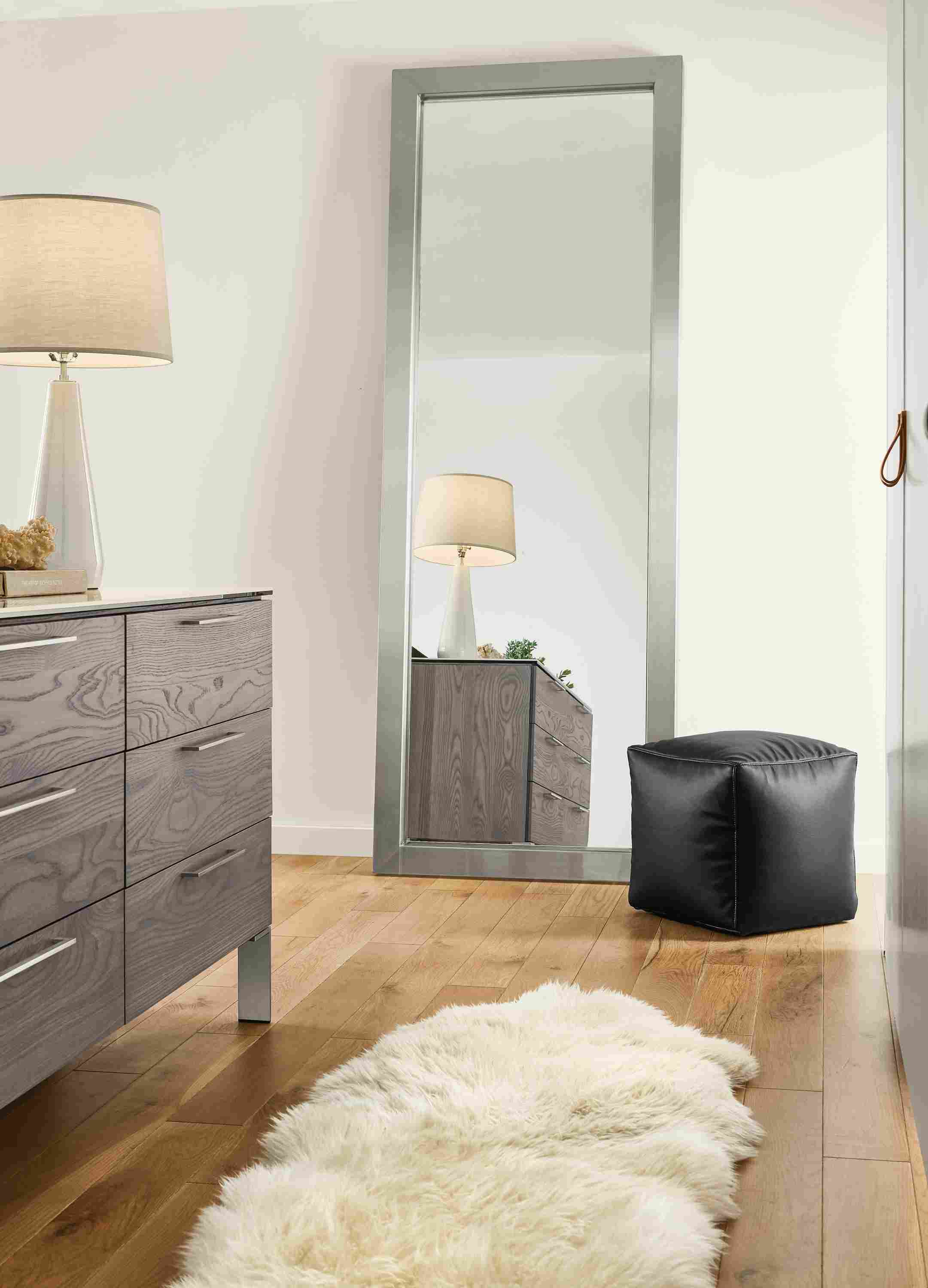 Detail of Industry leaning mirror in stainless steel in bedroom with Hux ottoman.