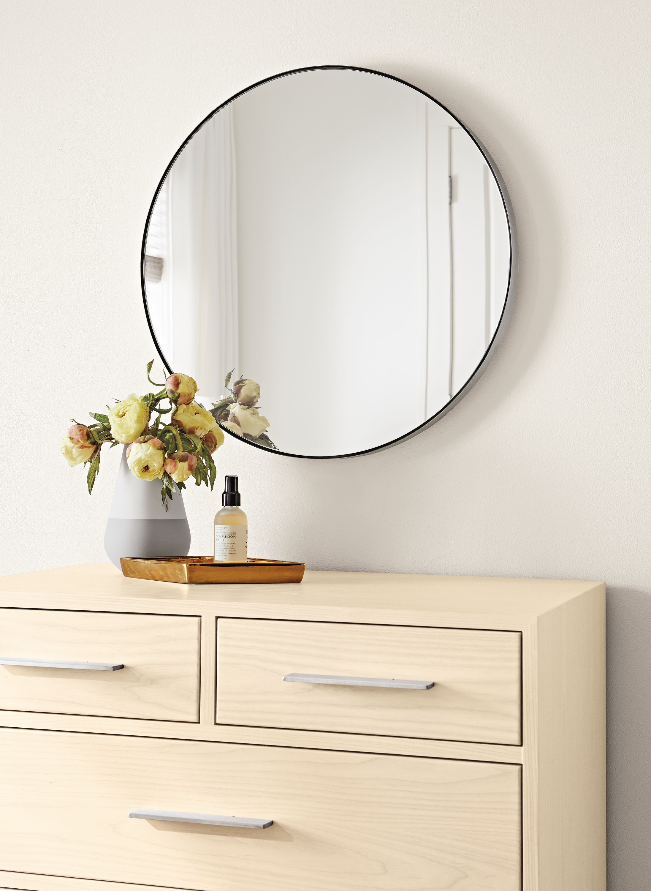Detail of Infinity custom round mirror in stainless steel above an Alden 4-drawer dresser in sand.