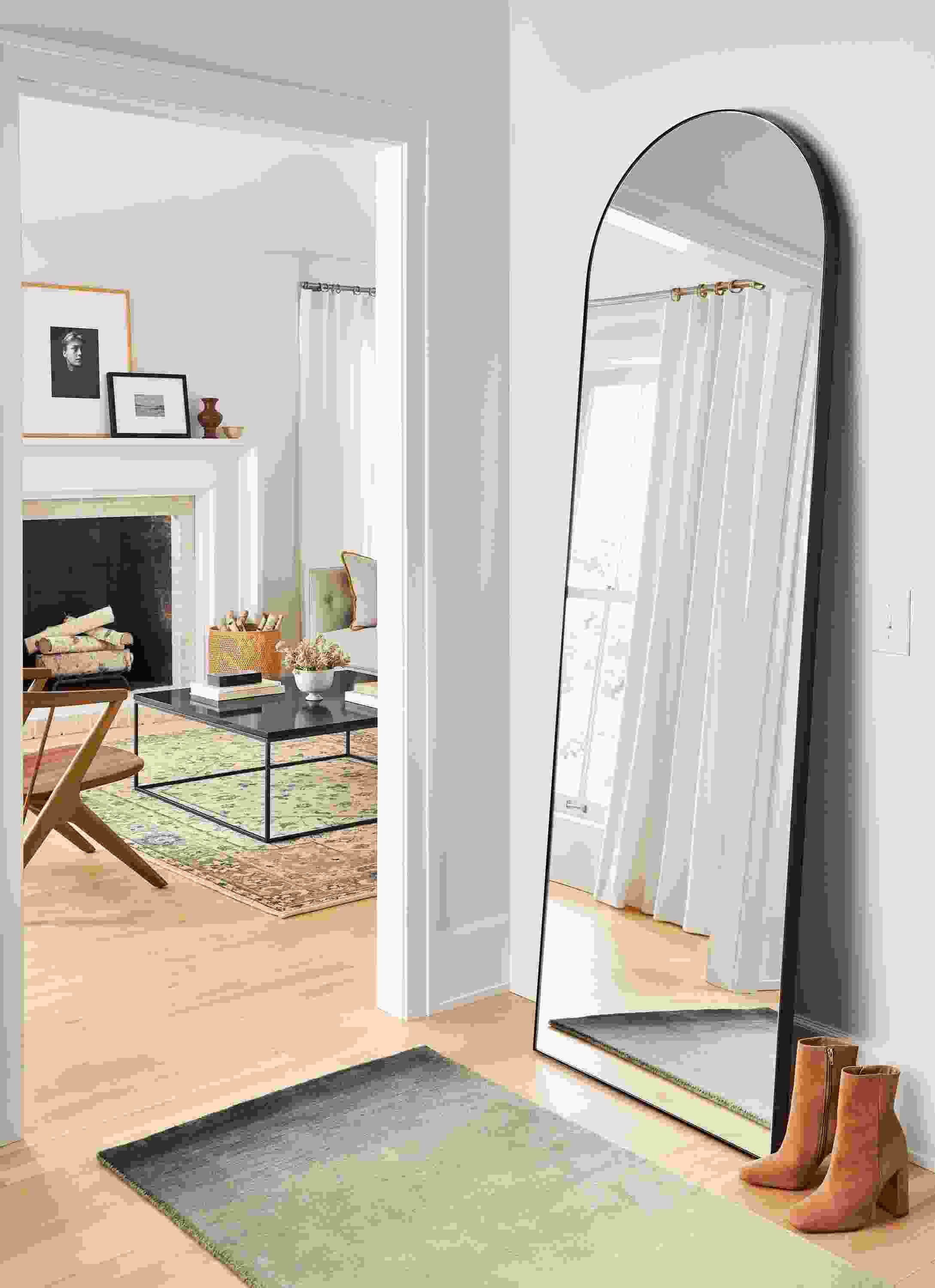 Detail of arched infinity floor mirror in onyx gloss in an entryway and a Luco rug in slate.