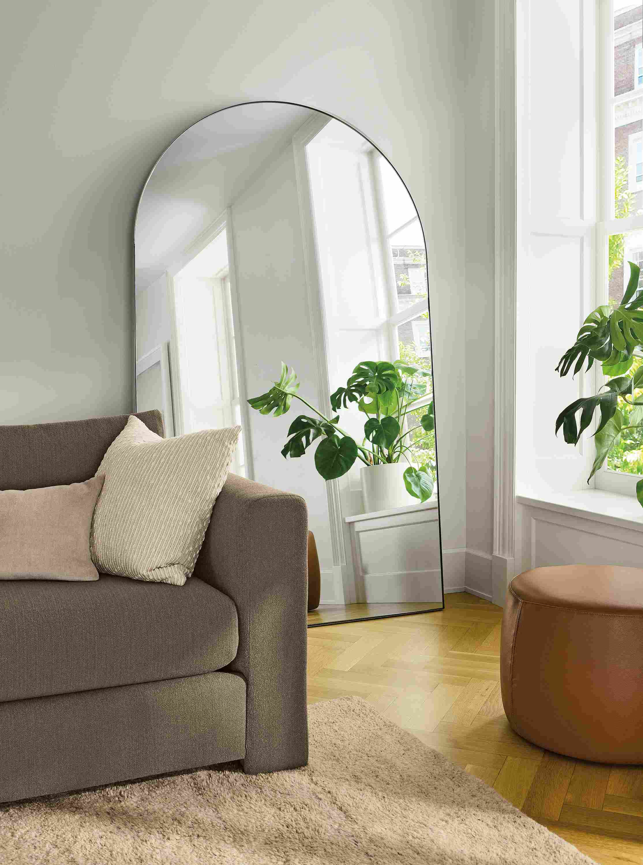Living room with Infinity 48-wide arched floor mirror in stainless steel and Hannah sofa in dusk mink.