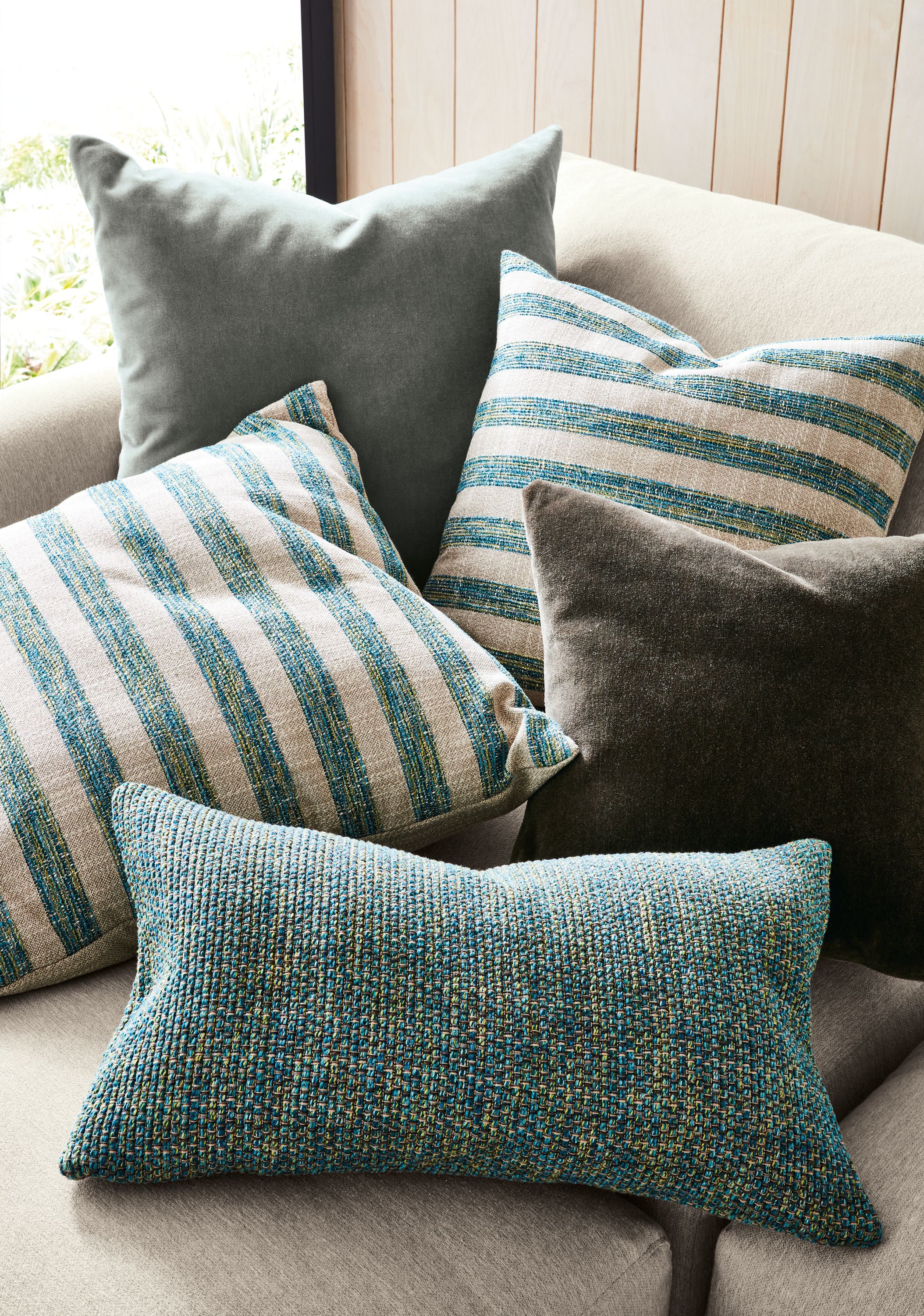 Group of pillows including Interlude and Arcade in Teal, Mohair in sky and charcoal on a Clemens sofa.