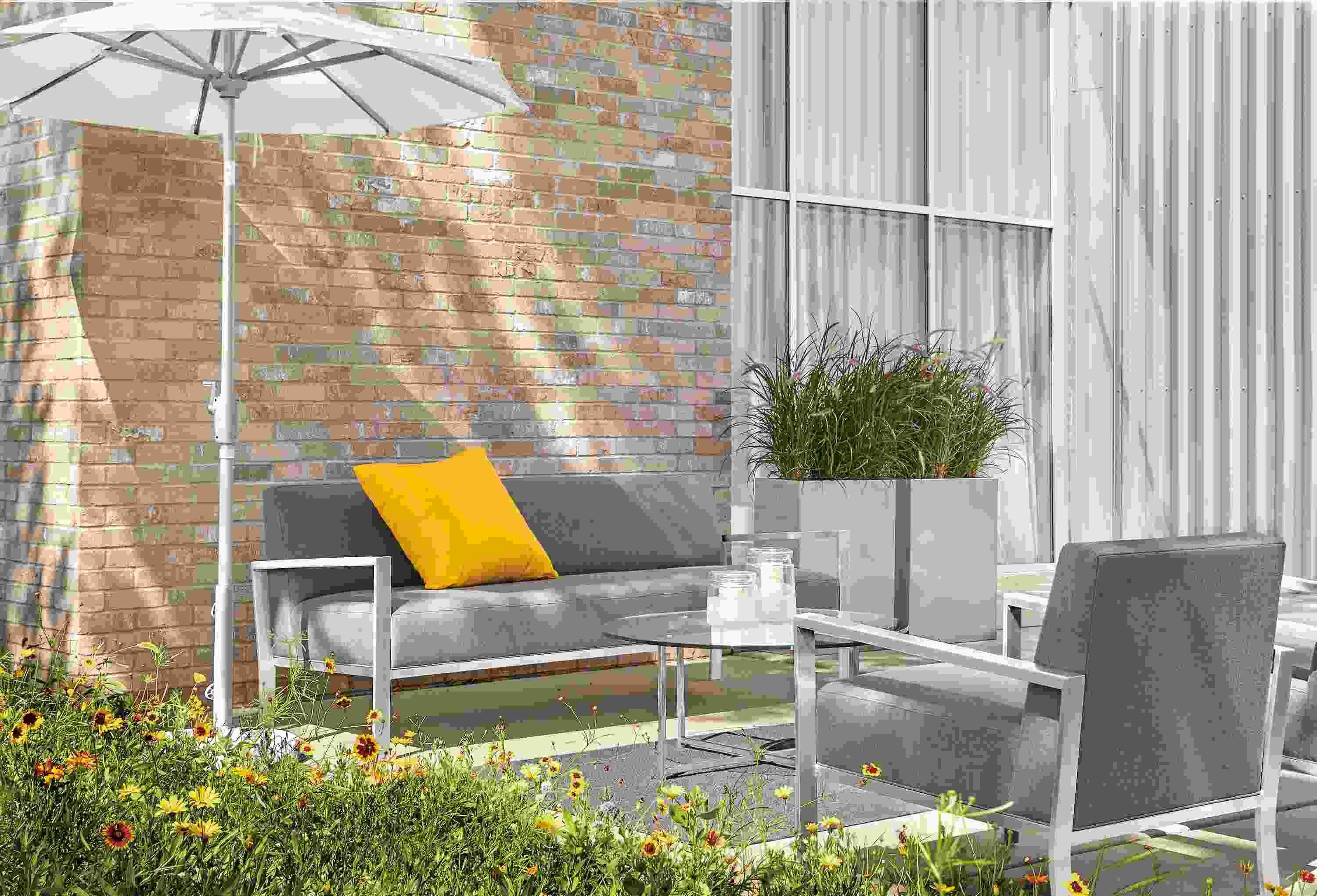Commercial patio with Isles sofa and chair in Sunbrella Canvas Slate and Maui umbrella.