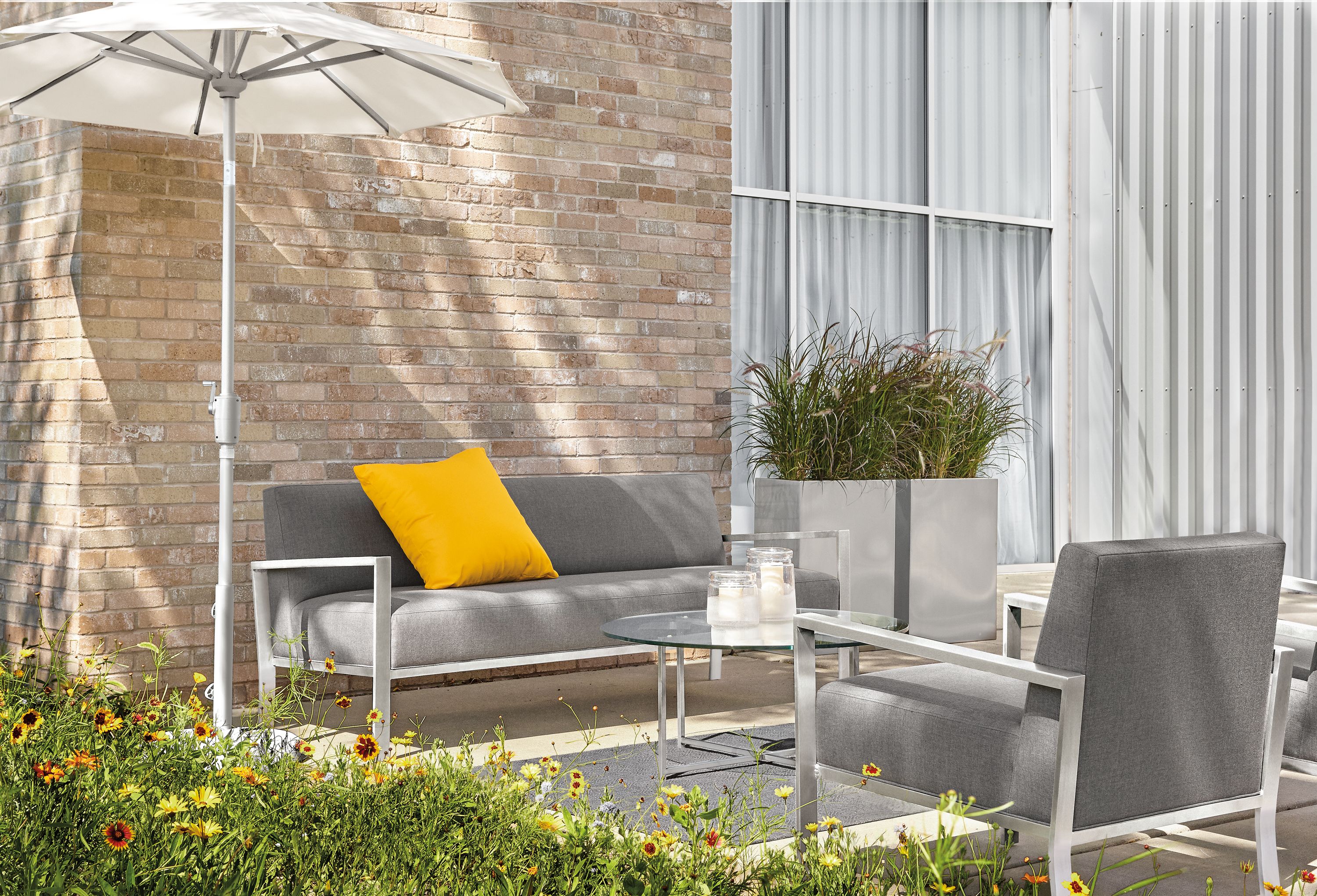 Commercial patio with Isles sofa and chair in Sunbrella Canvas Slate and Maui umbrella.